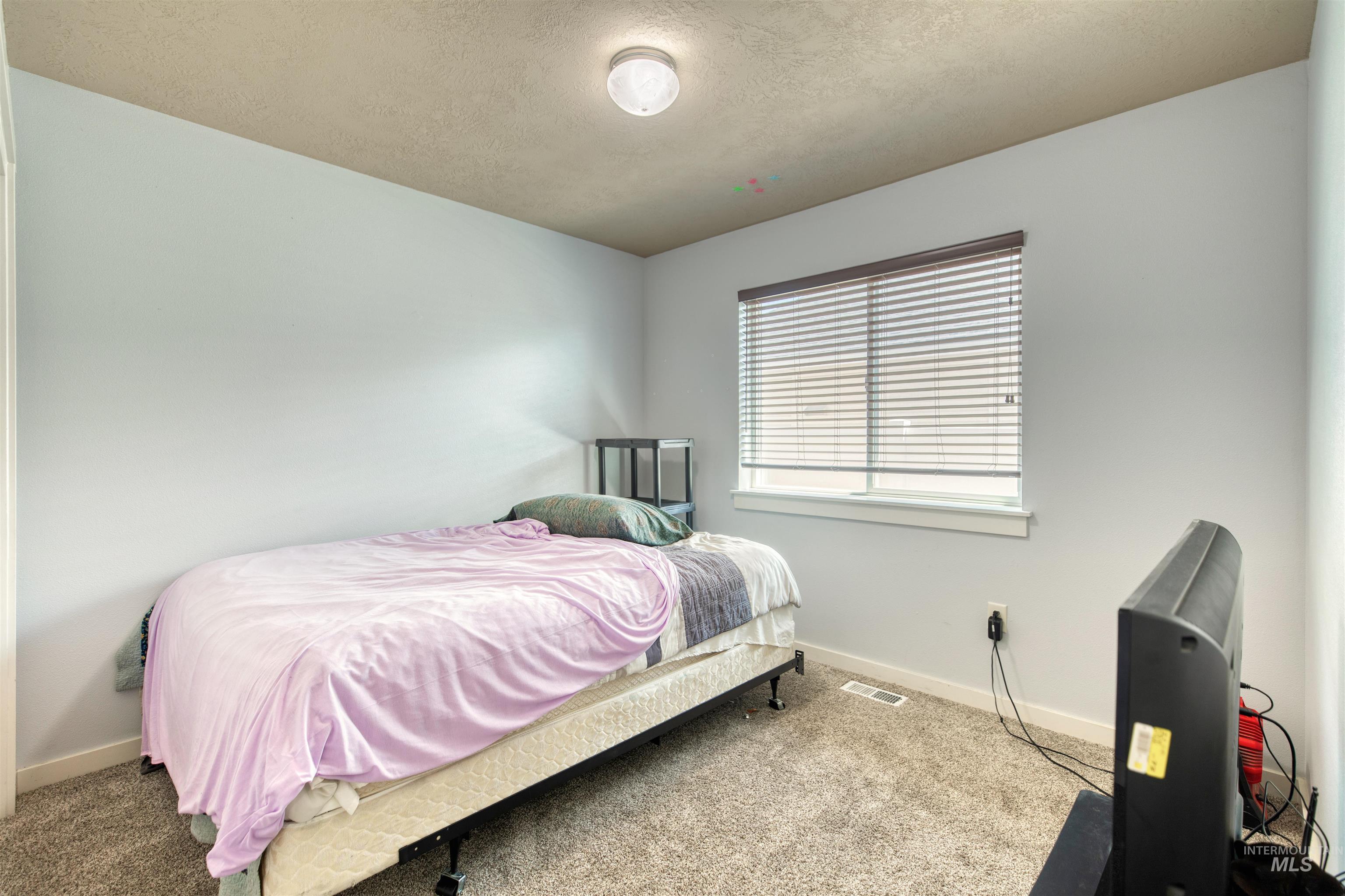 Bedroom featuring a textured ceiling and carpet