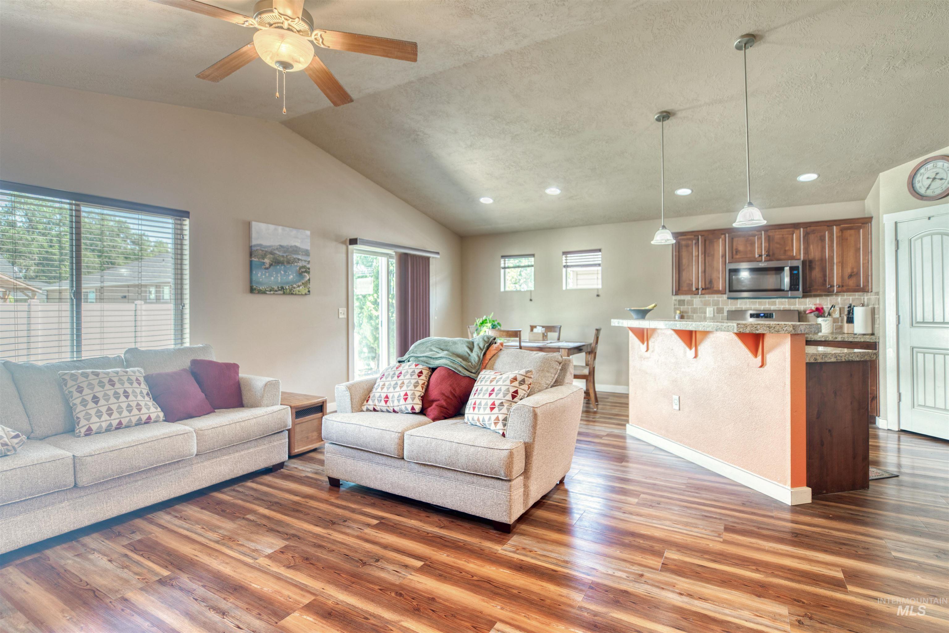 Living area with lofted ceiling, wood finished floors, recessed lighting, and ceiling fan