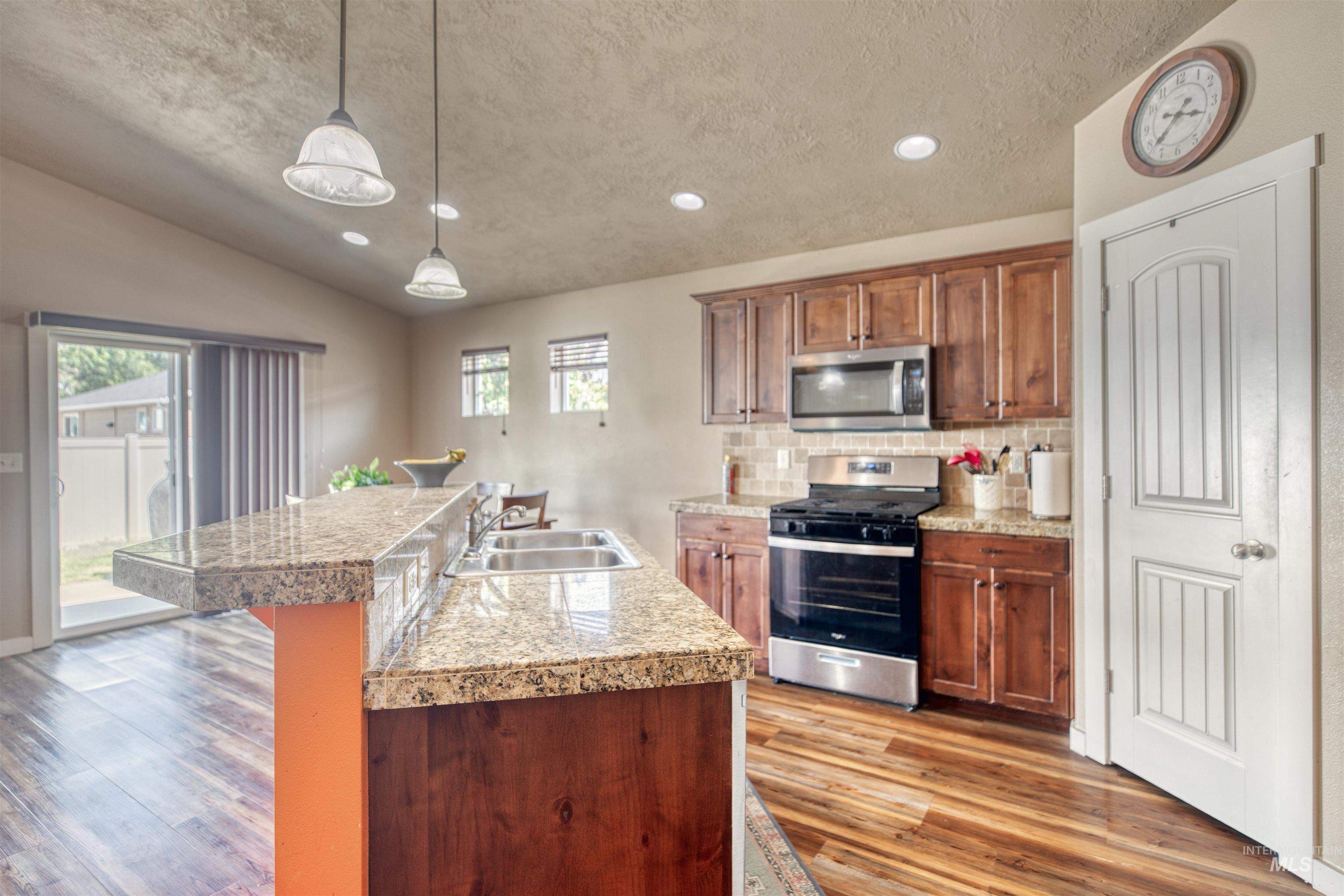 Kitchen featuring tile countertops, stainless steel appliances, lofted ceiling, recessed lighting, and light wood-style floors