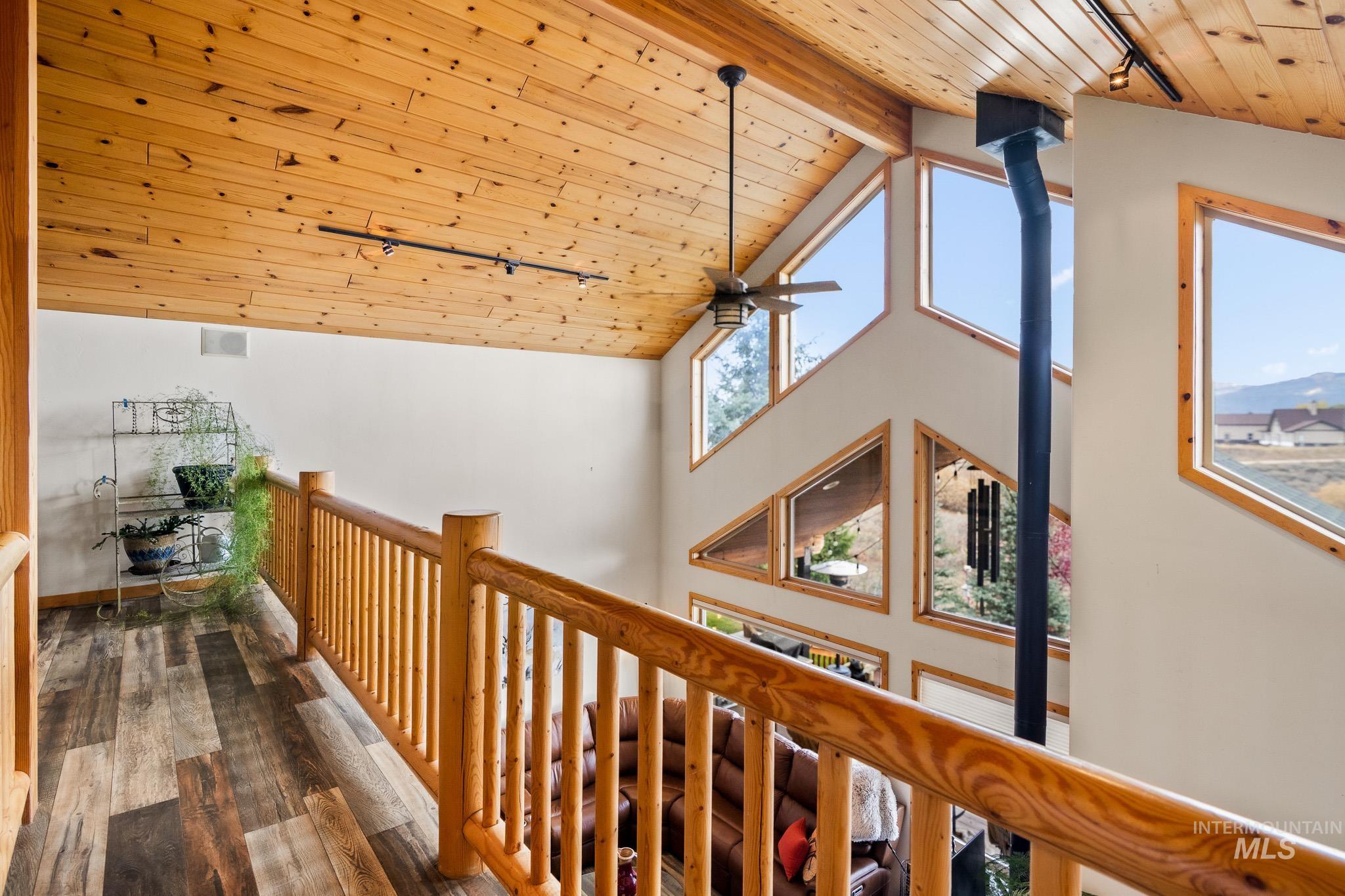 Hallway with a wood ceiling with exposed beams, wood finished floors, high vaulted ceiling, a mountain view, and track lighting