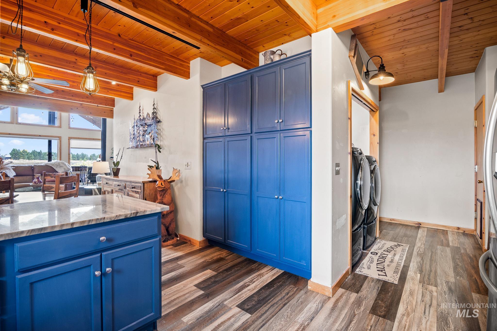 Kitchen with blue cabinets, pendant lighting, a wooden ceiling with exposed beams, light granite counters, and open floor plan