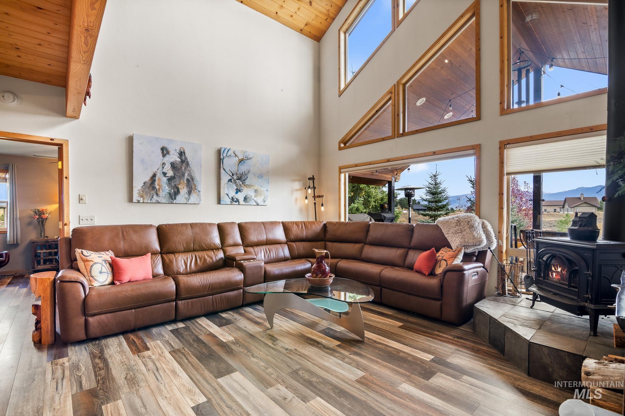 Great room featuring a wood stove, wood ceiling, EVP floors, and high vaulted ceiling