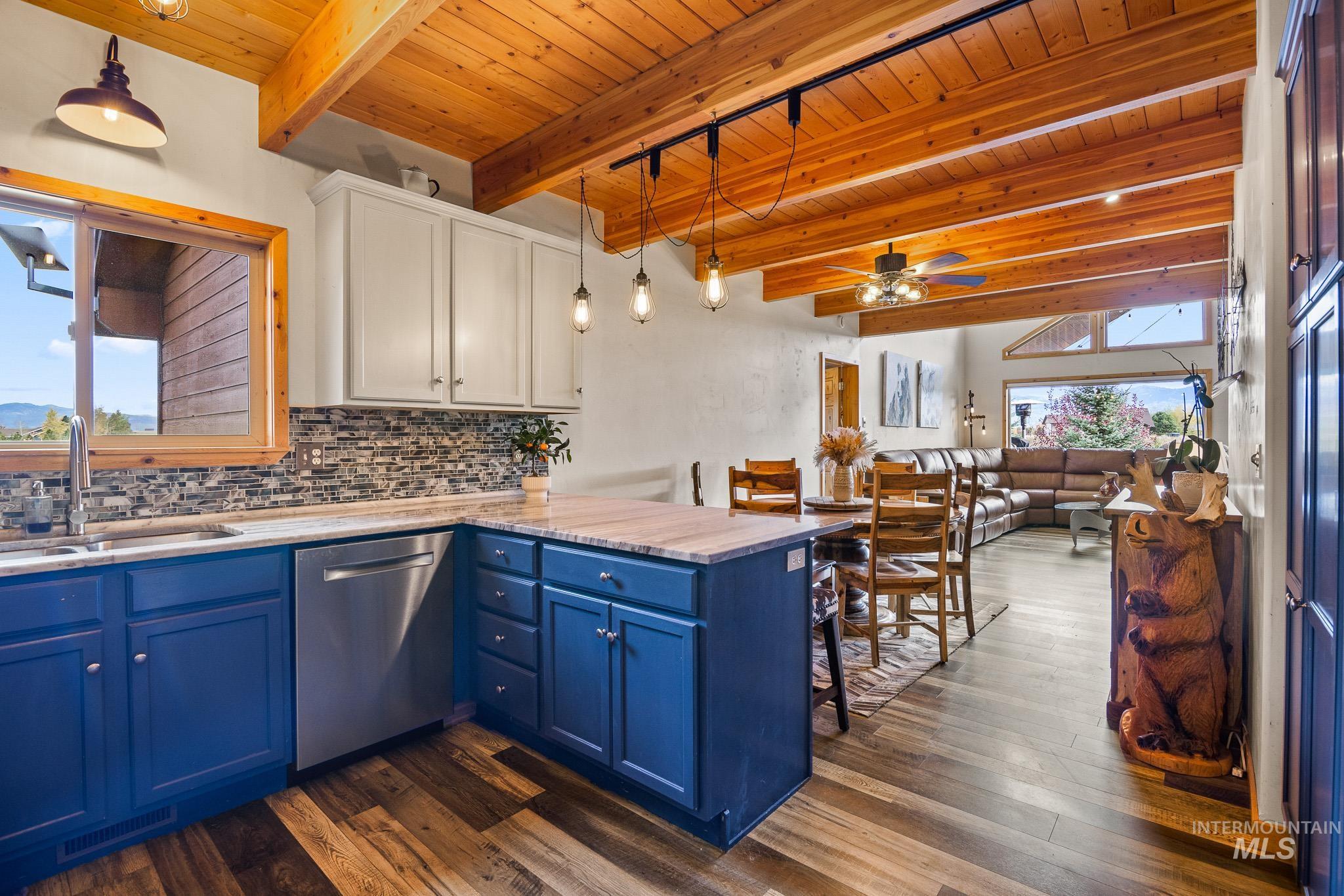 Kitchen featuring blue cabinets, decorative light fixtures, decorative backsplash, a peninsula, and a wood ceiling with exposed beams