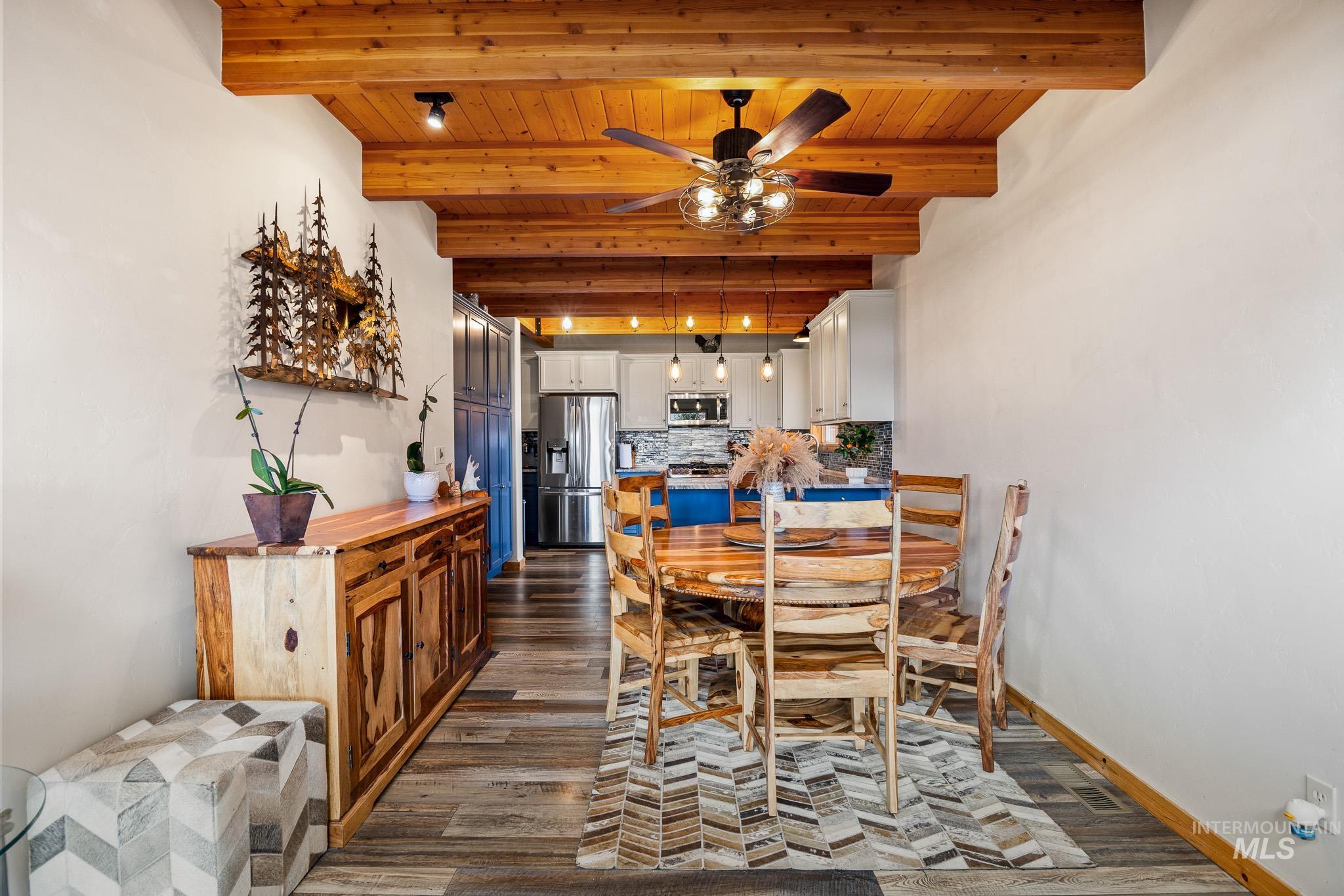 Dining area featuring a wood ceiling with exposed beams, dark wood-style floors, and ceiling fan