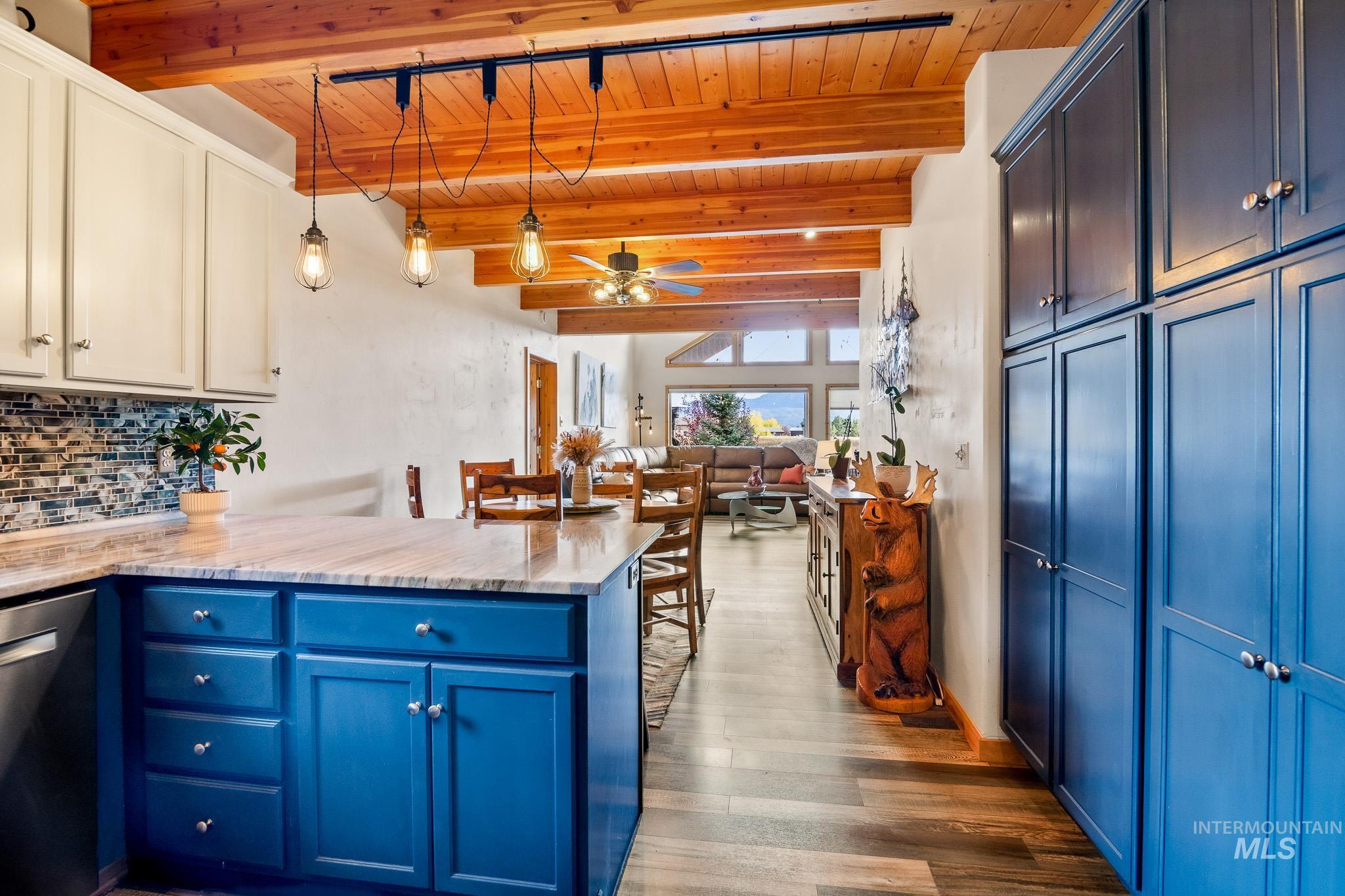 Kitchen featuring blue cabinetry, hanging light fixtures, a peninsula, a wood ceiling with exposed beams, and dishwasher