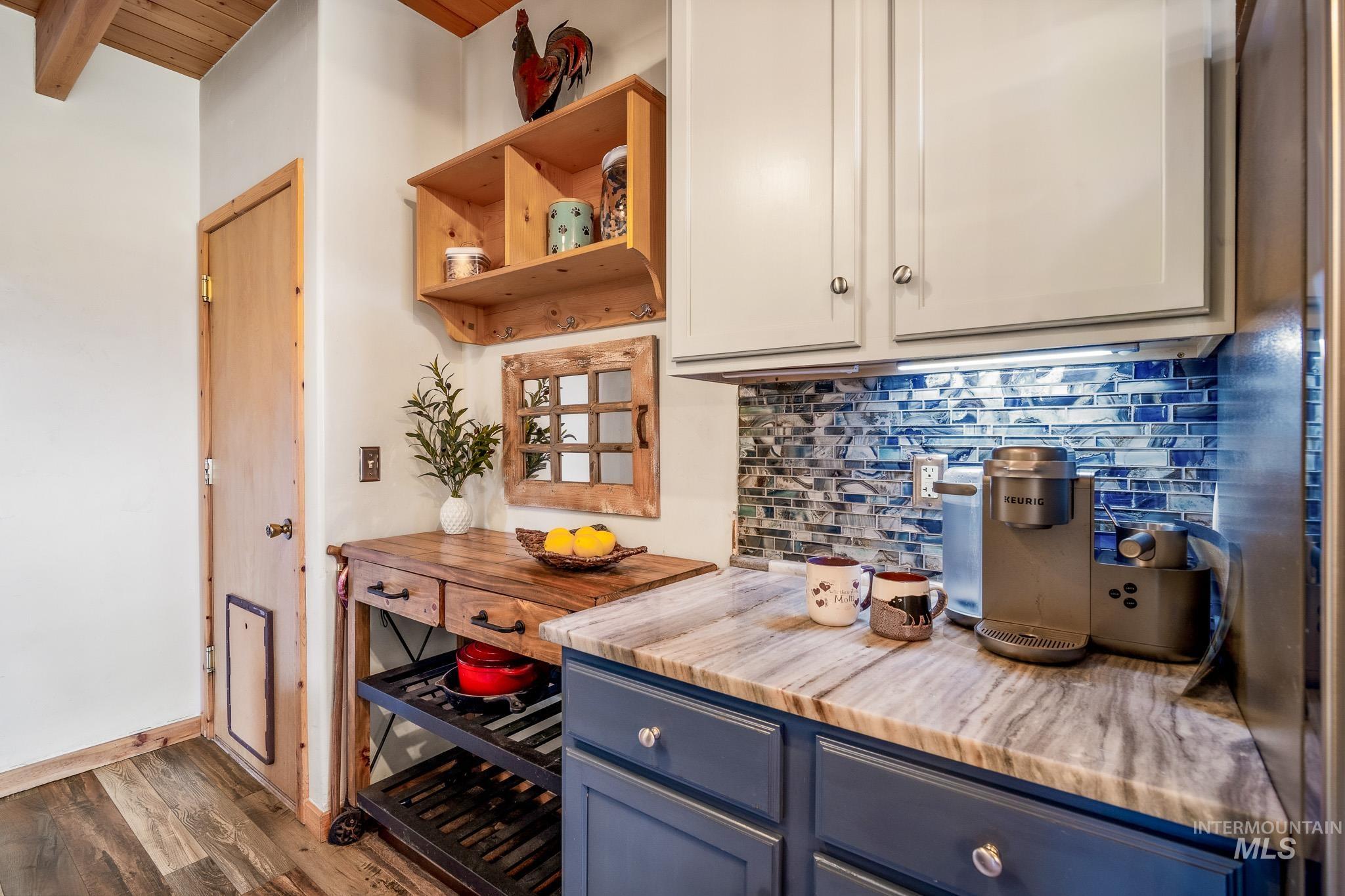 Bar area with backsplash, blue cabinetry, open shelves, and a wooden ceiling with exposed beams