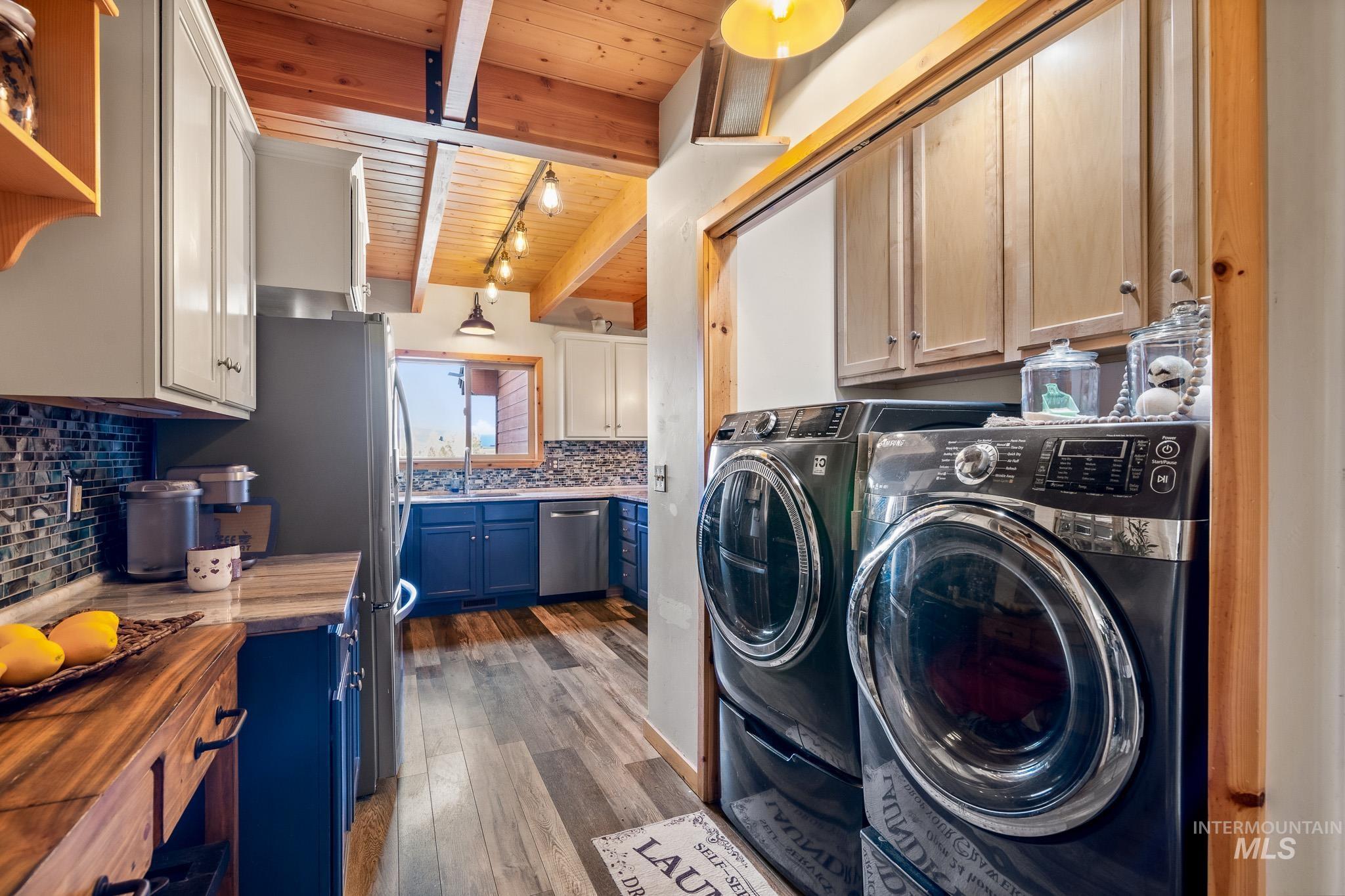 Laundry area featuring a wood ceiling with exposed beams, cabinet space, and track lighting