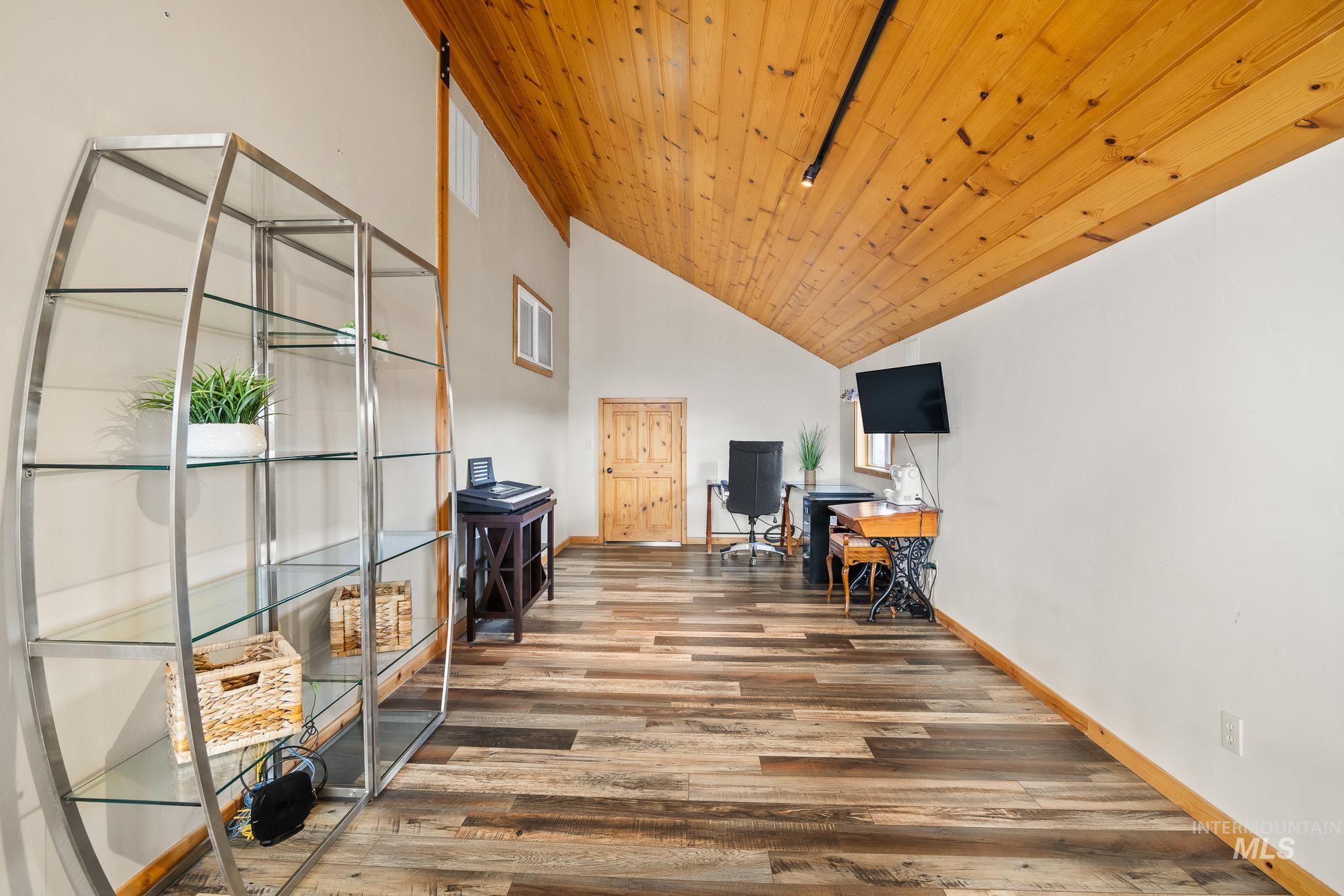 Living area with wood ceiling, high vaulted ceiling, and an office area with door to bonus room over garage