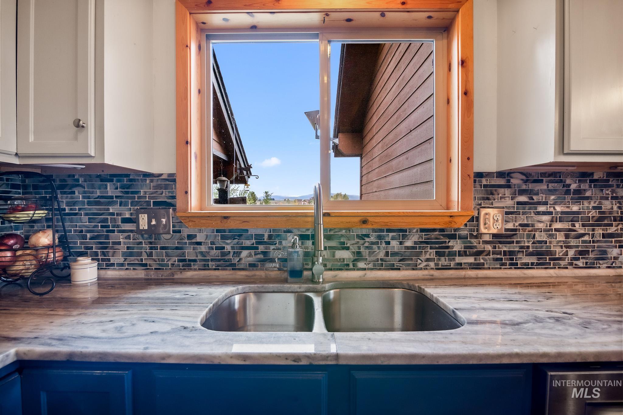 Kitchen with blue cabinetry, backsplash, and light granite counters