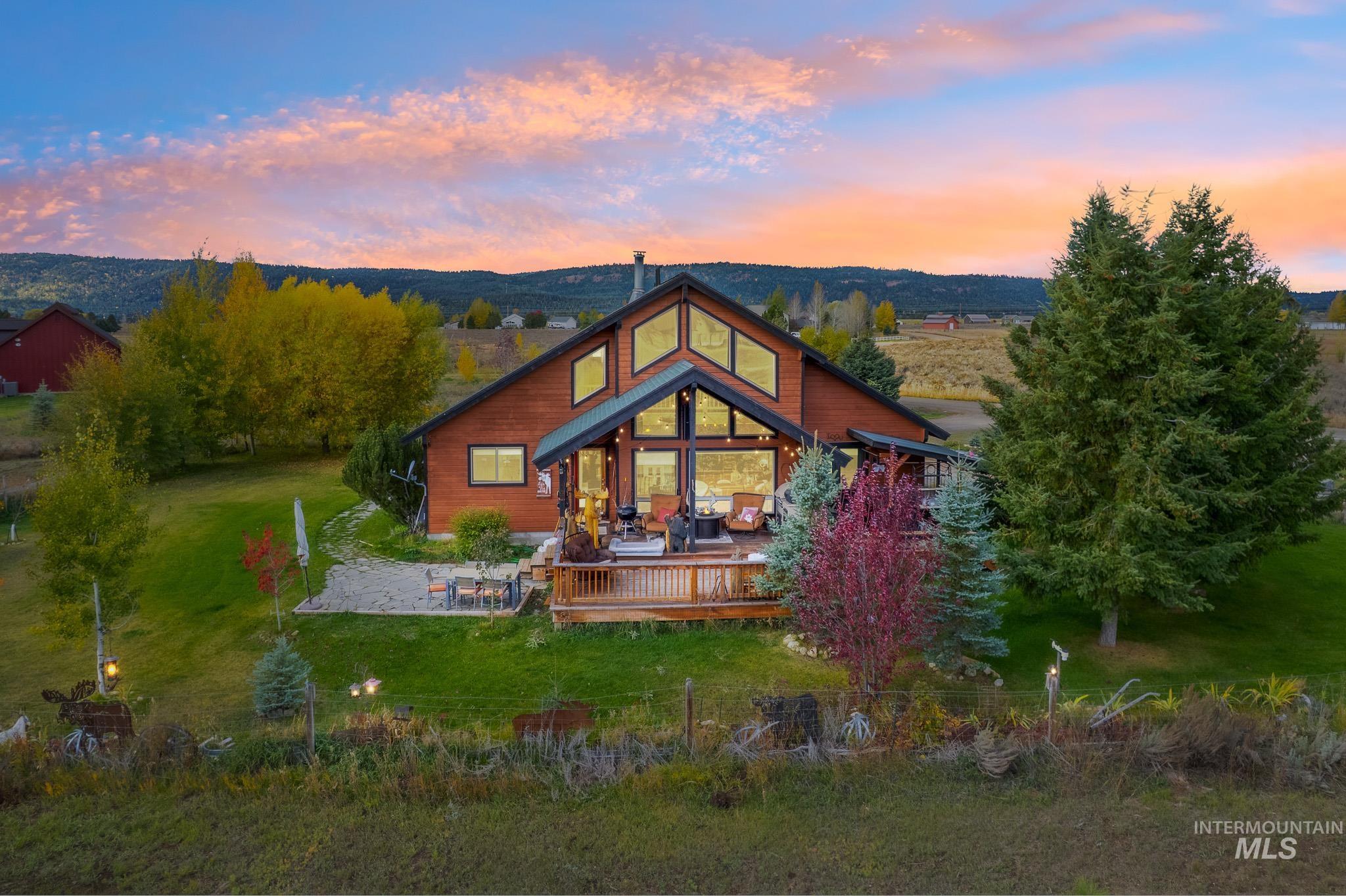 Front of property at dusk featuring a yard, a wooden deck, and outdoor lounge area