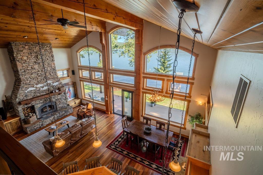 Double-height living space featuring a stone fireplace, wood-finish flooring, and a beamed wood ceiling