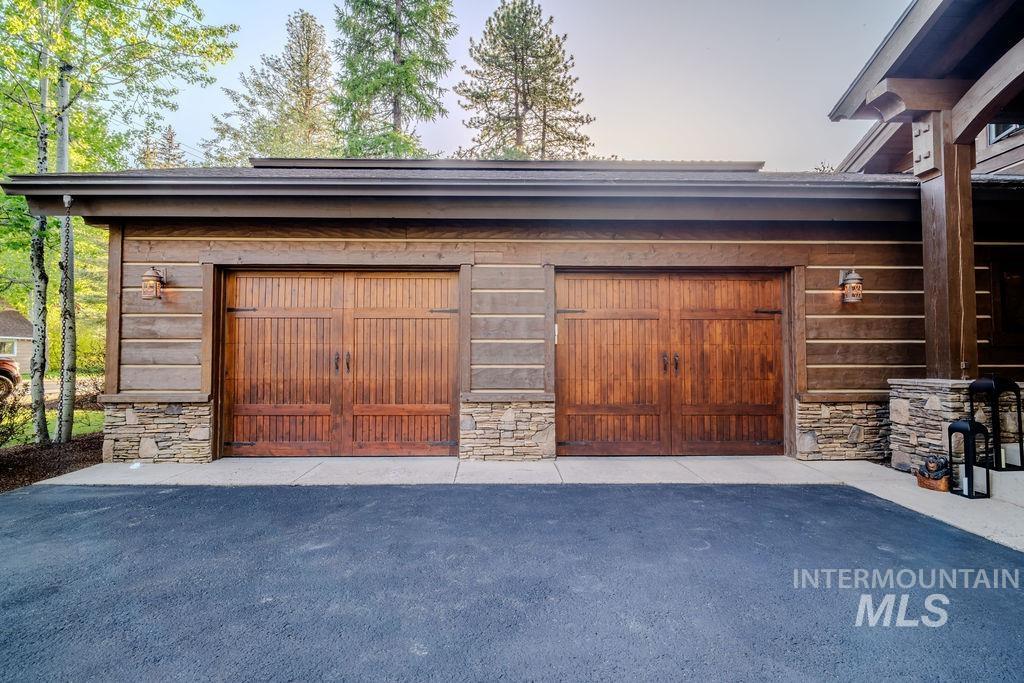 Two-car garage featuring rich wood-finish doors and stone veneer accents