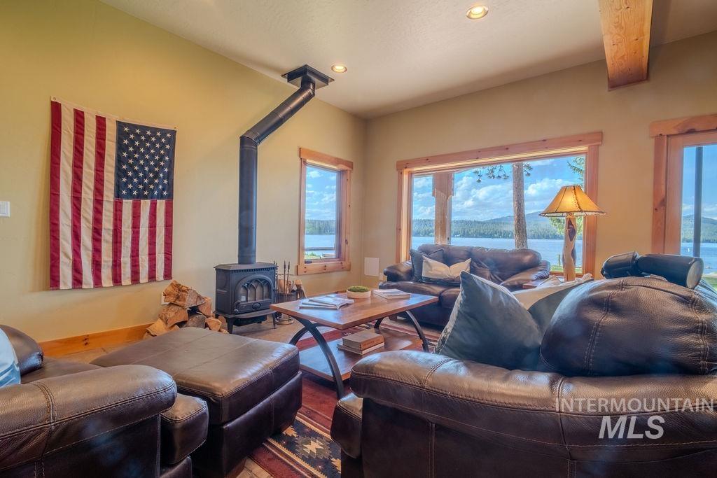 Spacious living area featuring a wood-burning stove, exposed ceiling beam, and recessed lighting