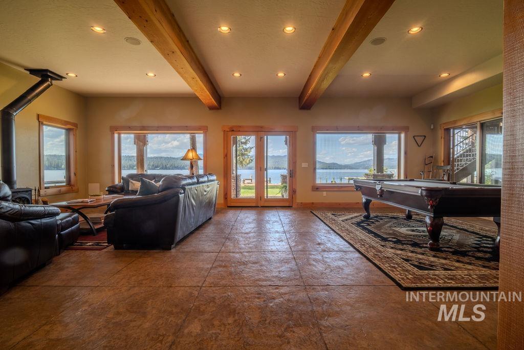 Spacious room featuring stamped concrete flooring, exposed wood ceiling beams, and recessed lighting