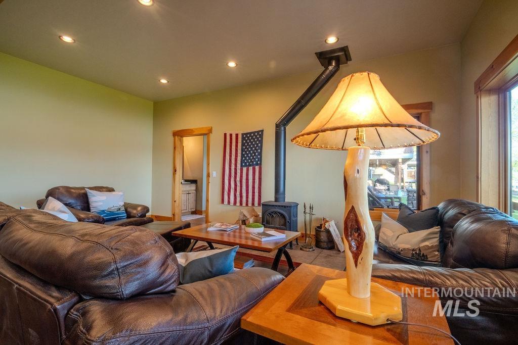 Interior living space featuring a wood-burning stove with a visible flue, recessed ceiling lighting, and natural wood trim around windows and doorways