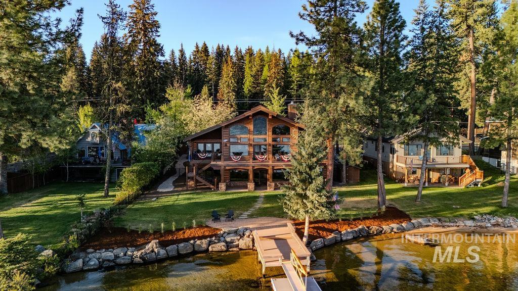 Log-style residence featuring a multi-level deck, a private dock extending into the water, and extensive window-frontage