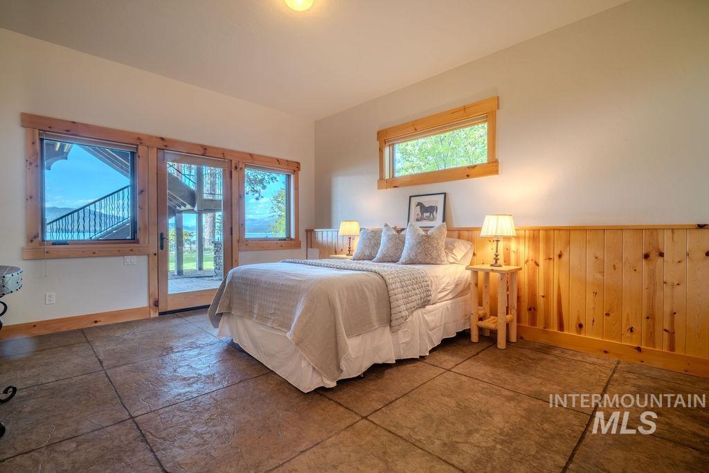 Stamped concrete flooring, wood-paneled wall, natural wood window and door trim, and a glass-paneled exterior door