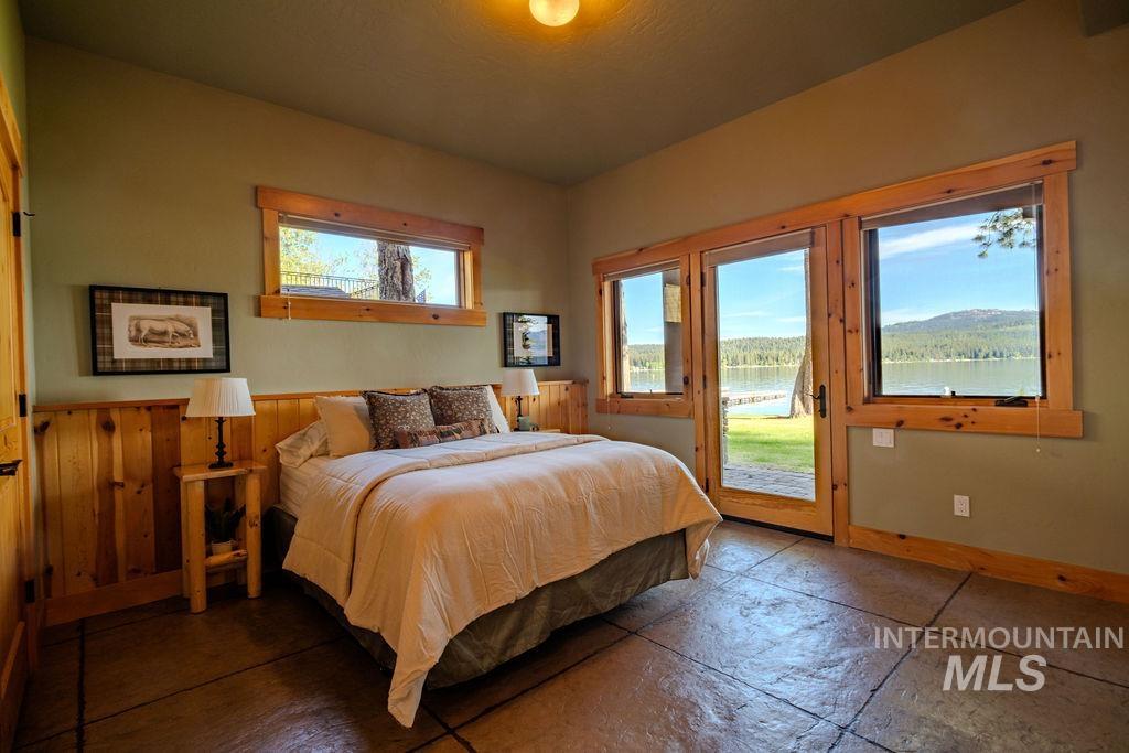 Bedroom featuring expansive windows with wood trim, offering exterior water and mountain scenery