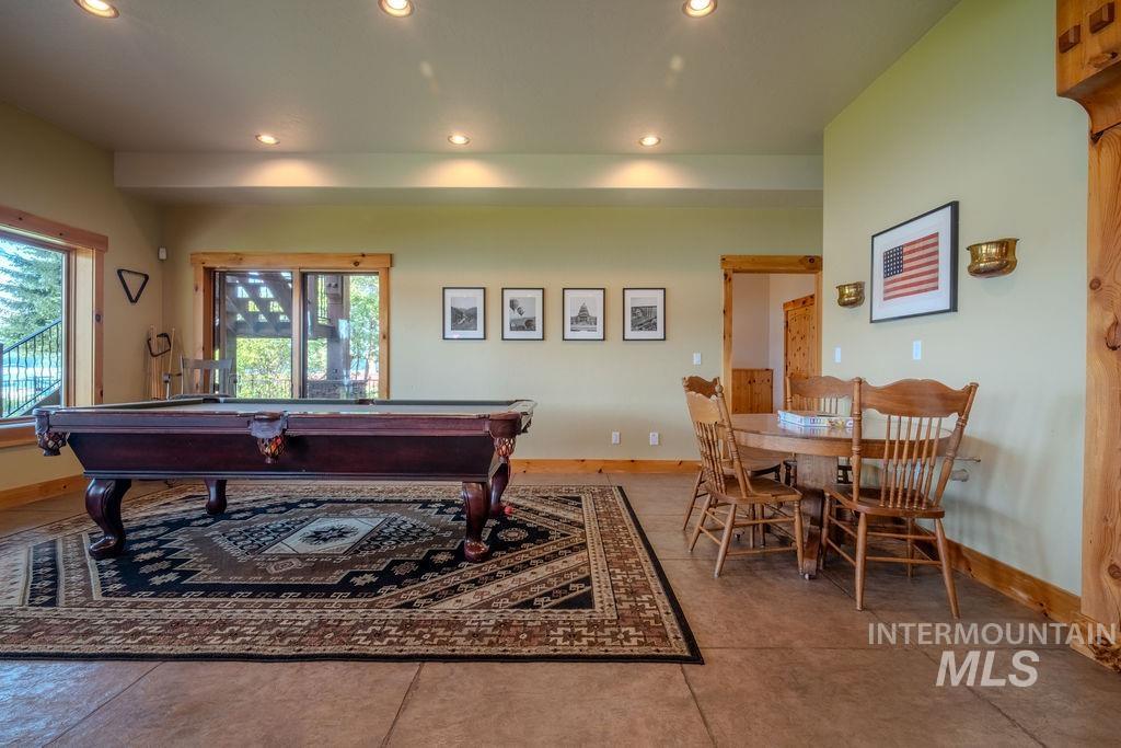 Spacious recreation area featuring recessed lighting, tile flooring, wood-framed windows, and a wood-framed sliding glass door