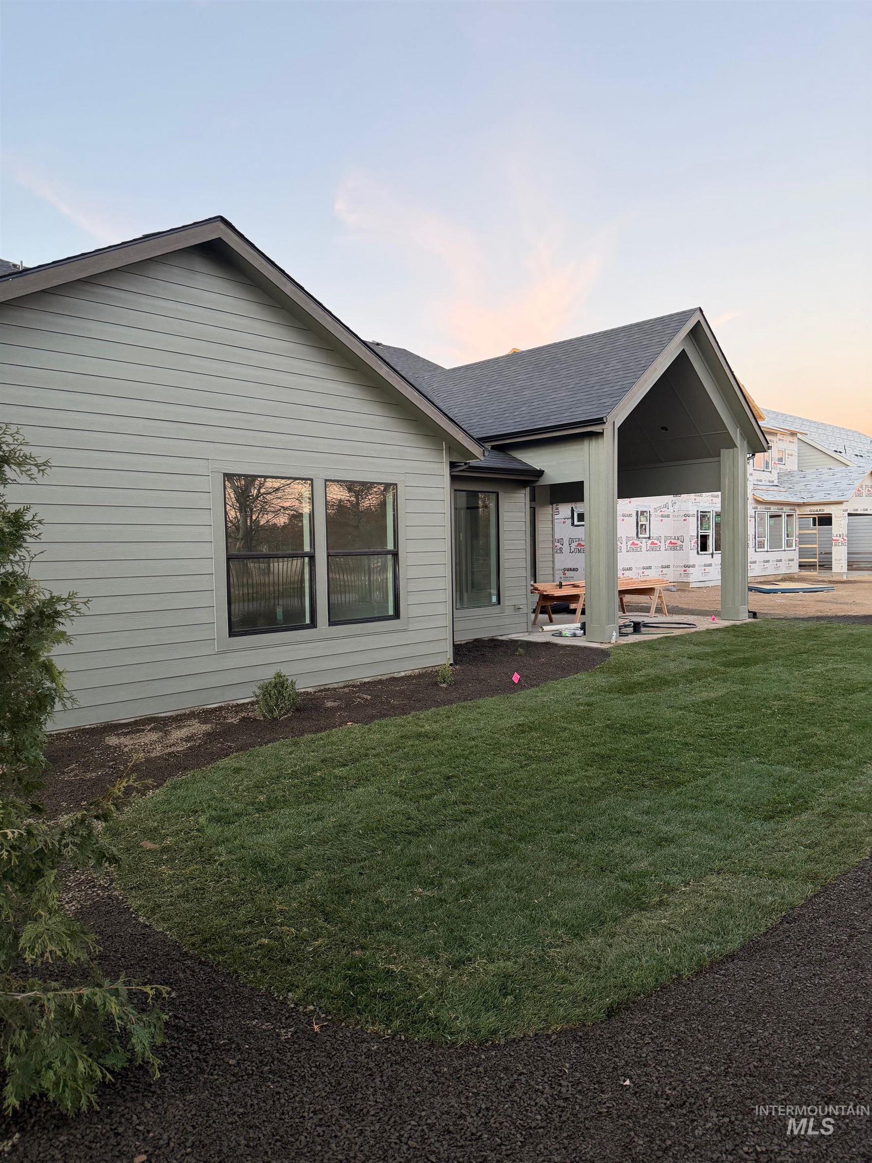 Back of house featuring a yard and roof with shingles