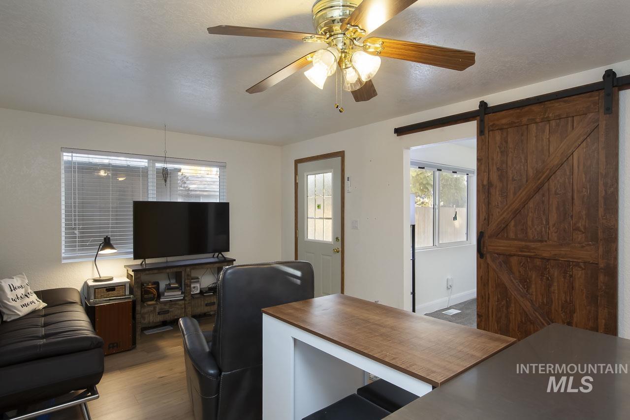 Home office featuring dark wood-style flooring, a barn door, and ceiling fan