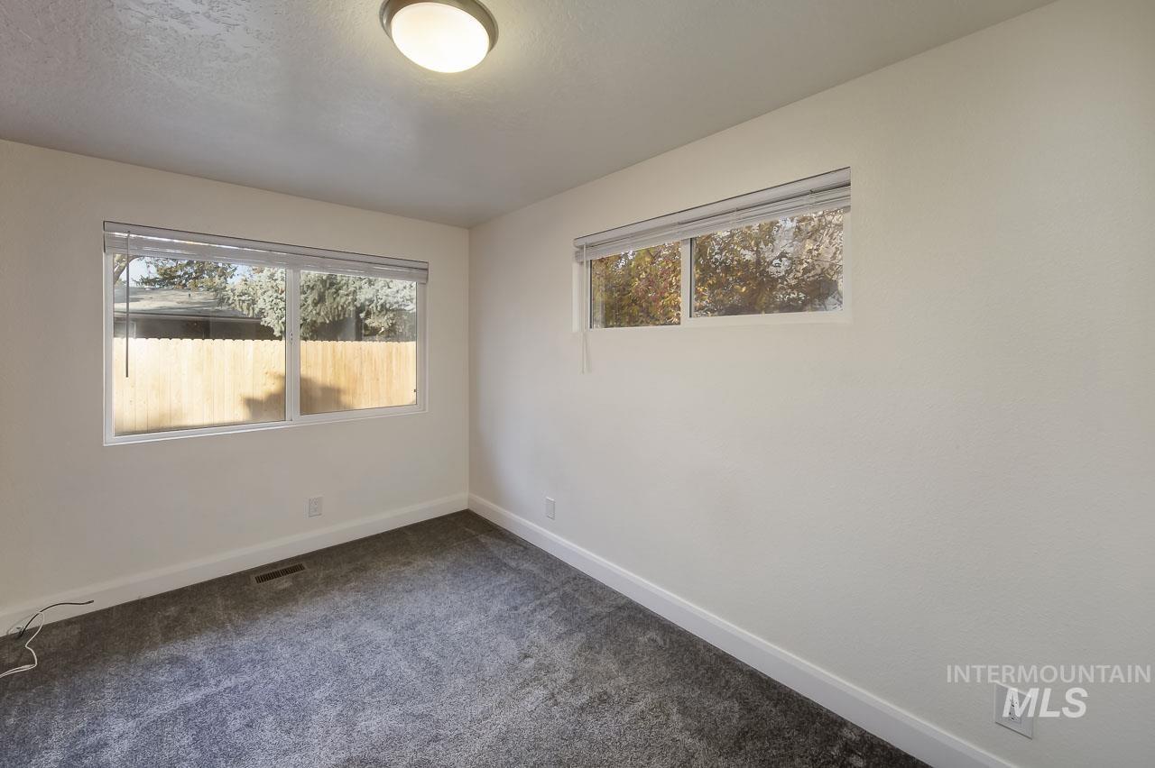 Empty room with plenty of natural light and dark colored carpet
