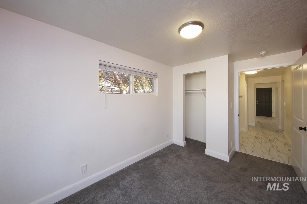 Unfurnished bedroom with a closet, dark colored carpet, and a textured ceiling