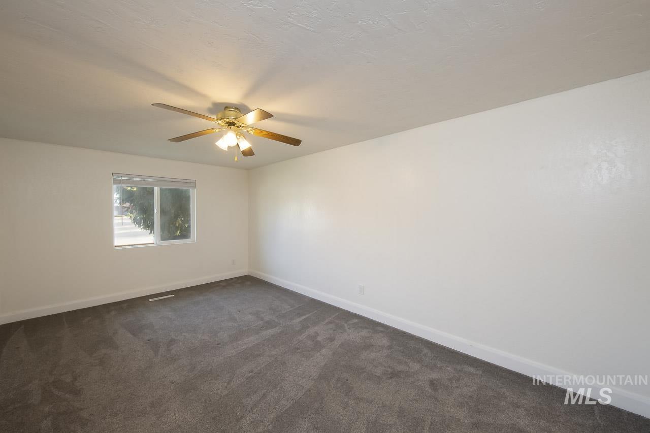 Unfurnished room with dark carpet and ceiling fan