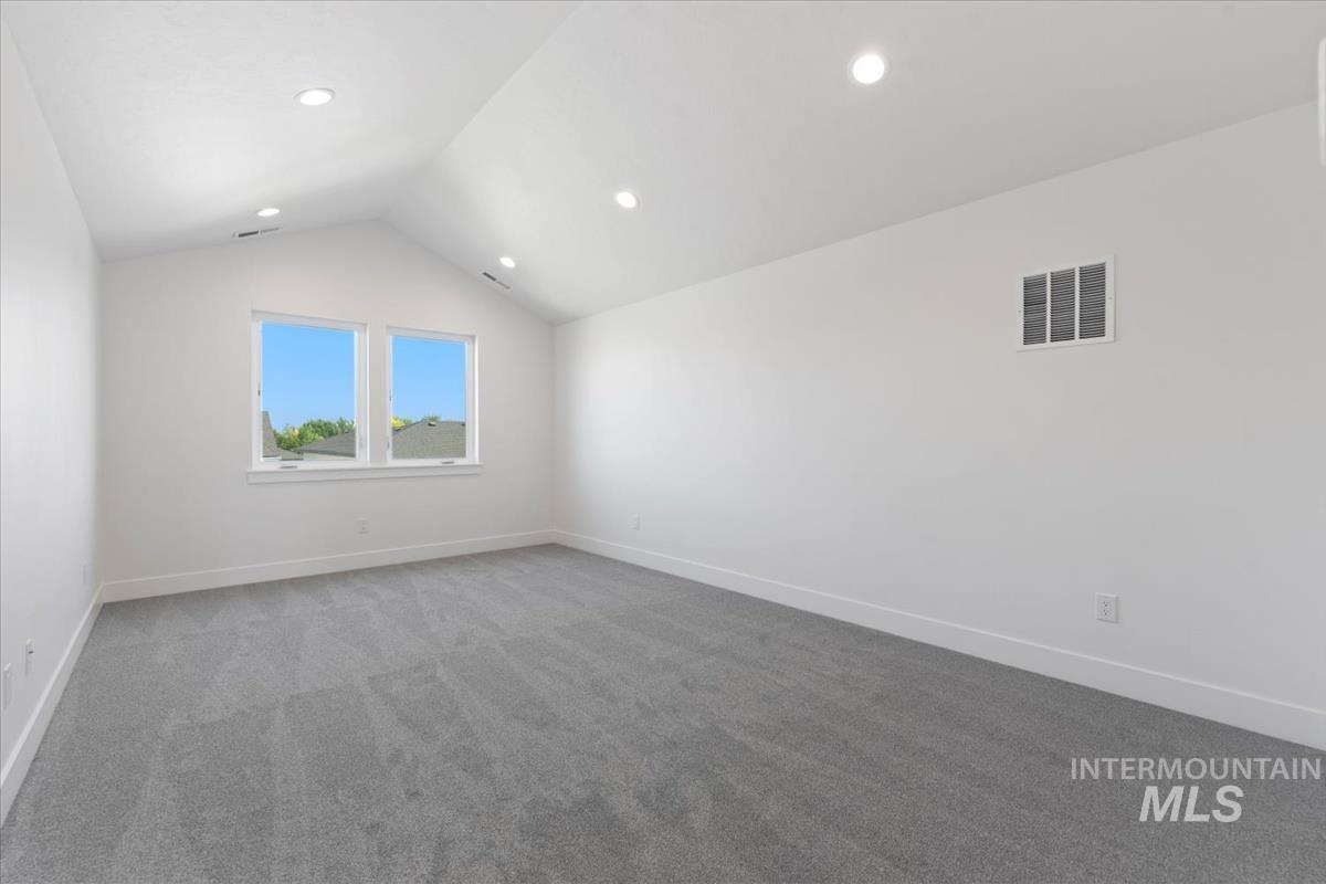 Additional living space with vaulted ceiling and light carpet