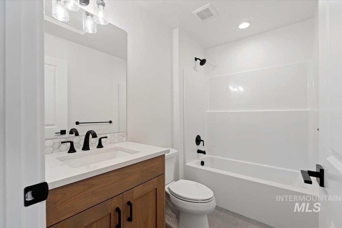 Bathroom featuring vanity,  shower combination, light tile patterned flooring, recessed lighting, and a chandelier