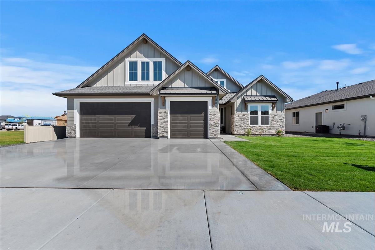 View of front facade with board and batten siding, a front lawn, driveway, and stone siding