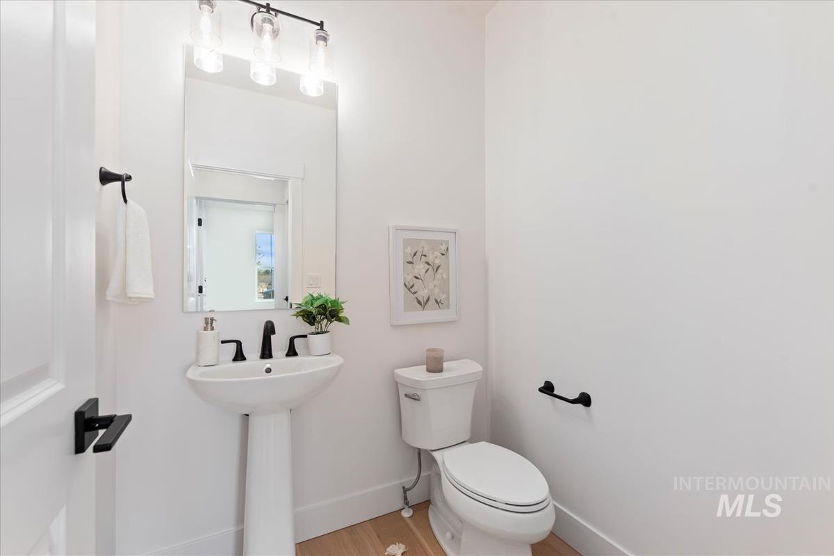 Half bathroom featuring toilet and wood finished floors