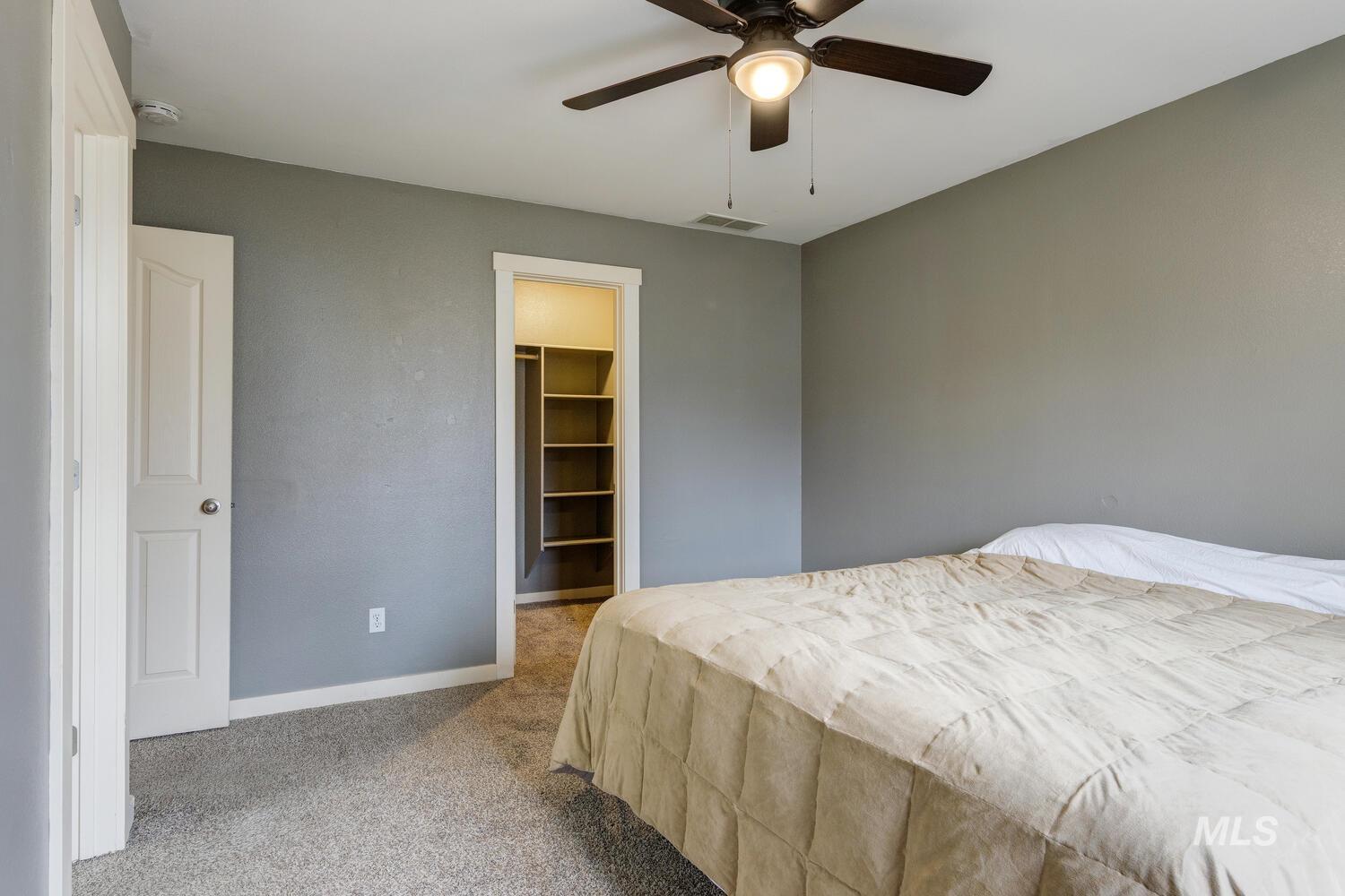 Bedroom with light carpet, a spacious closet, and ceiling fan