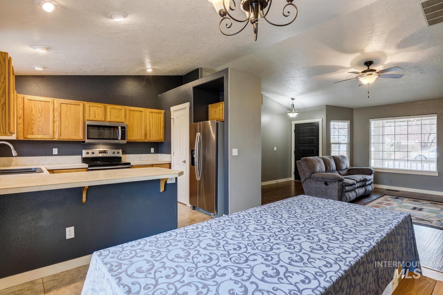 Kitchen with light countertops, lofted ceiling, stainless steel appliances, a breakfast bar, and a peninsula