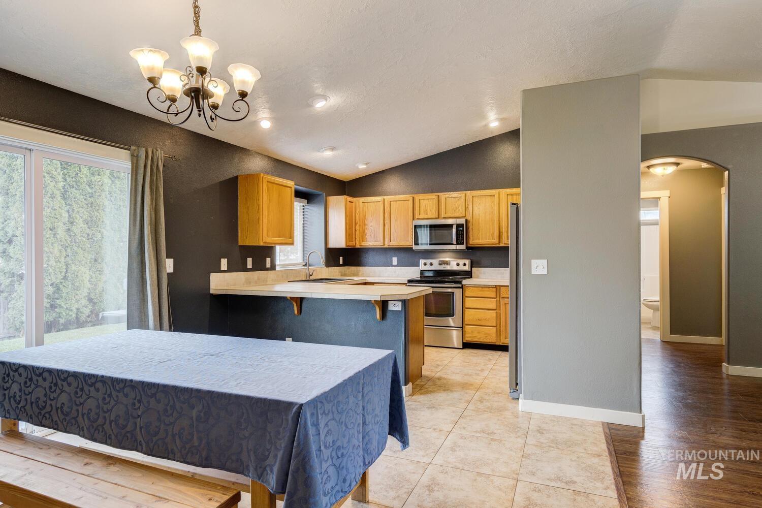 Kitchen featuring arched walkways, light countertops, lofted ceiling, a kitchen bar, and stainless steel appliances