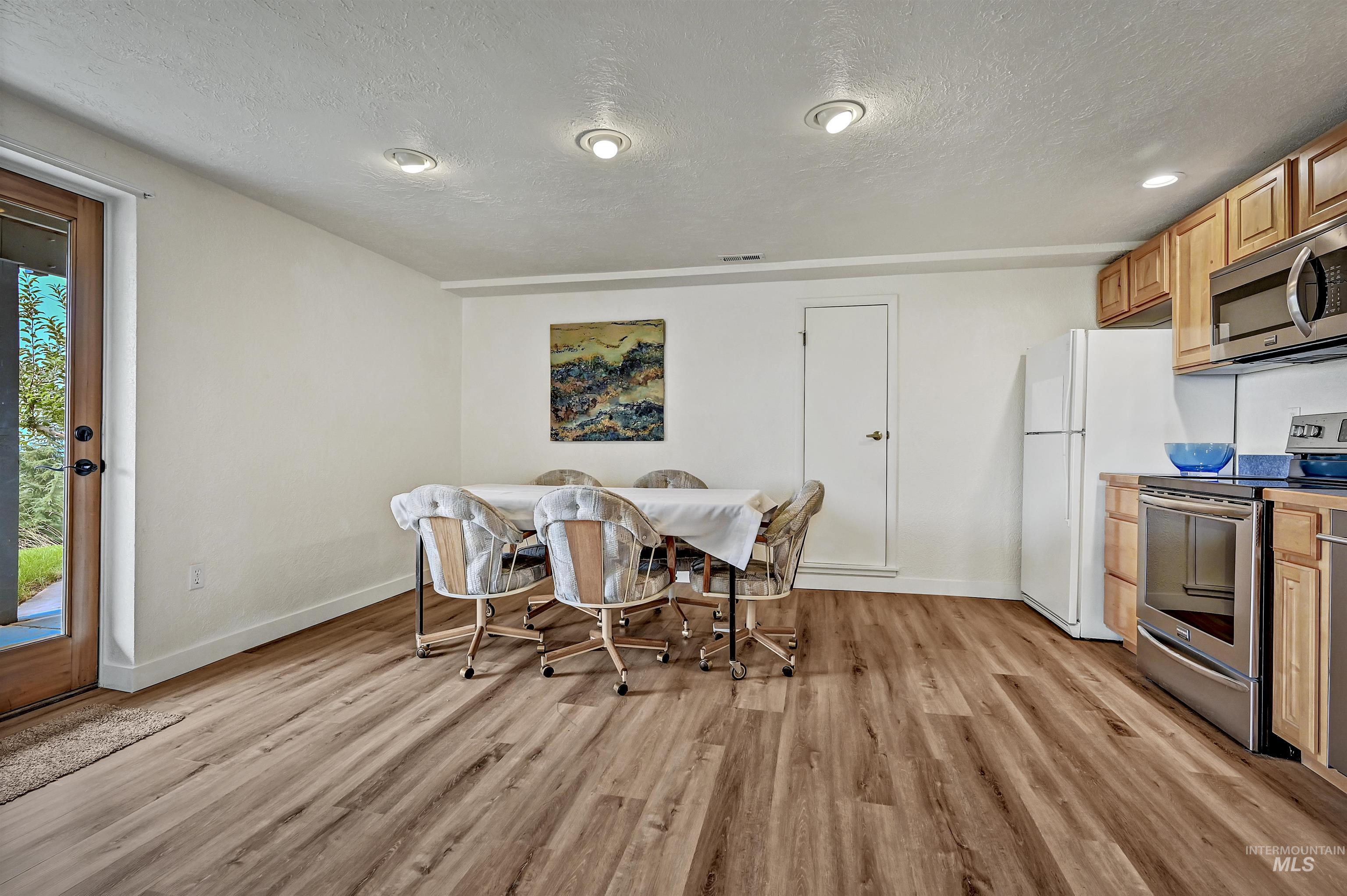 Dining room with light wood-style flooring and a textured ceiling