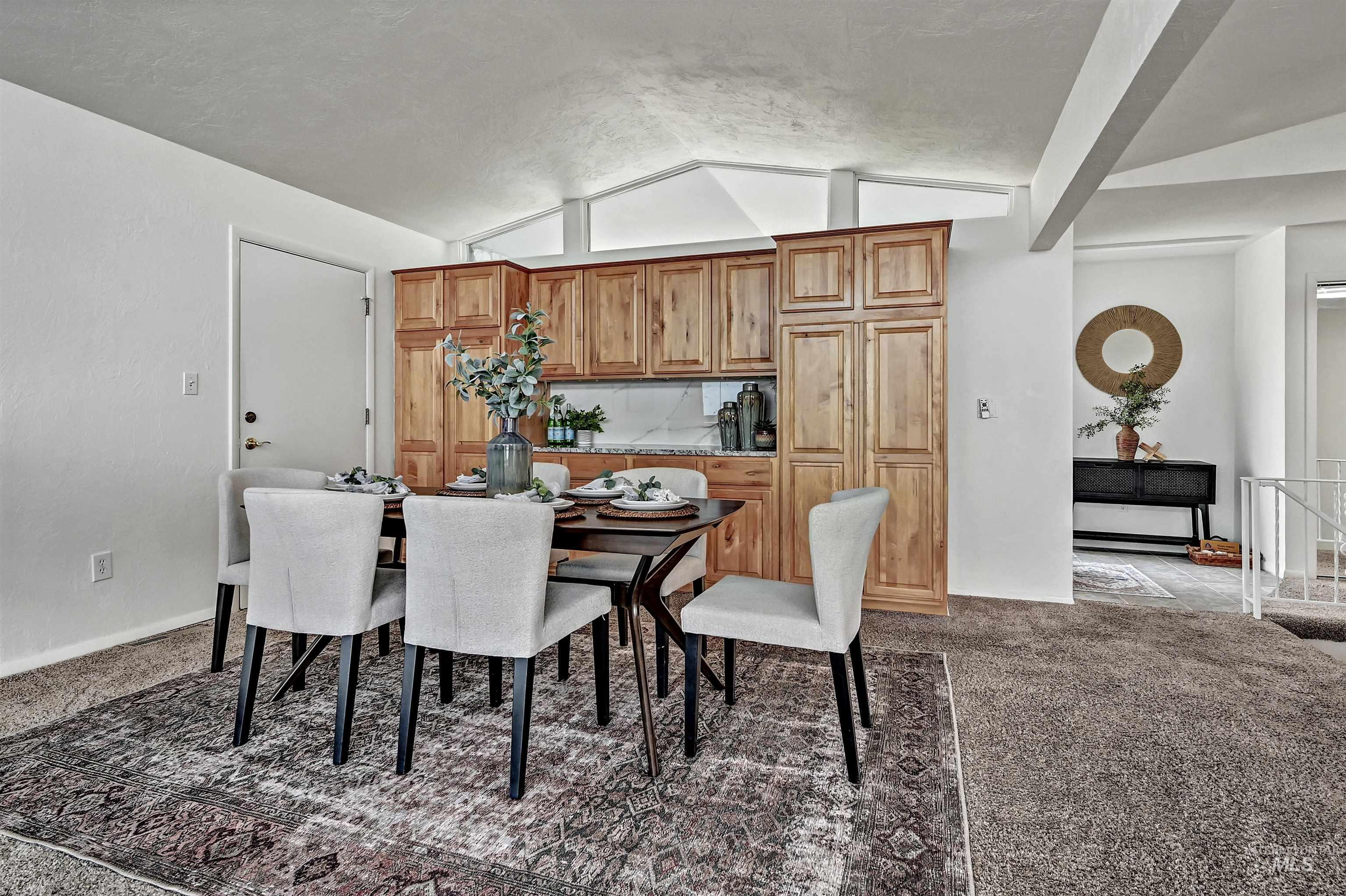 Dining room with lofted ceiling and dark colored carpet