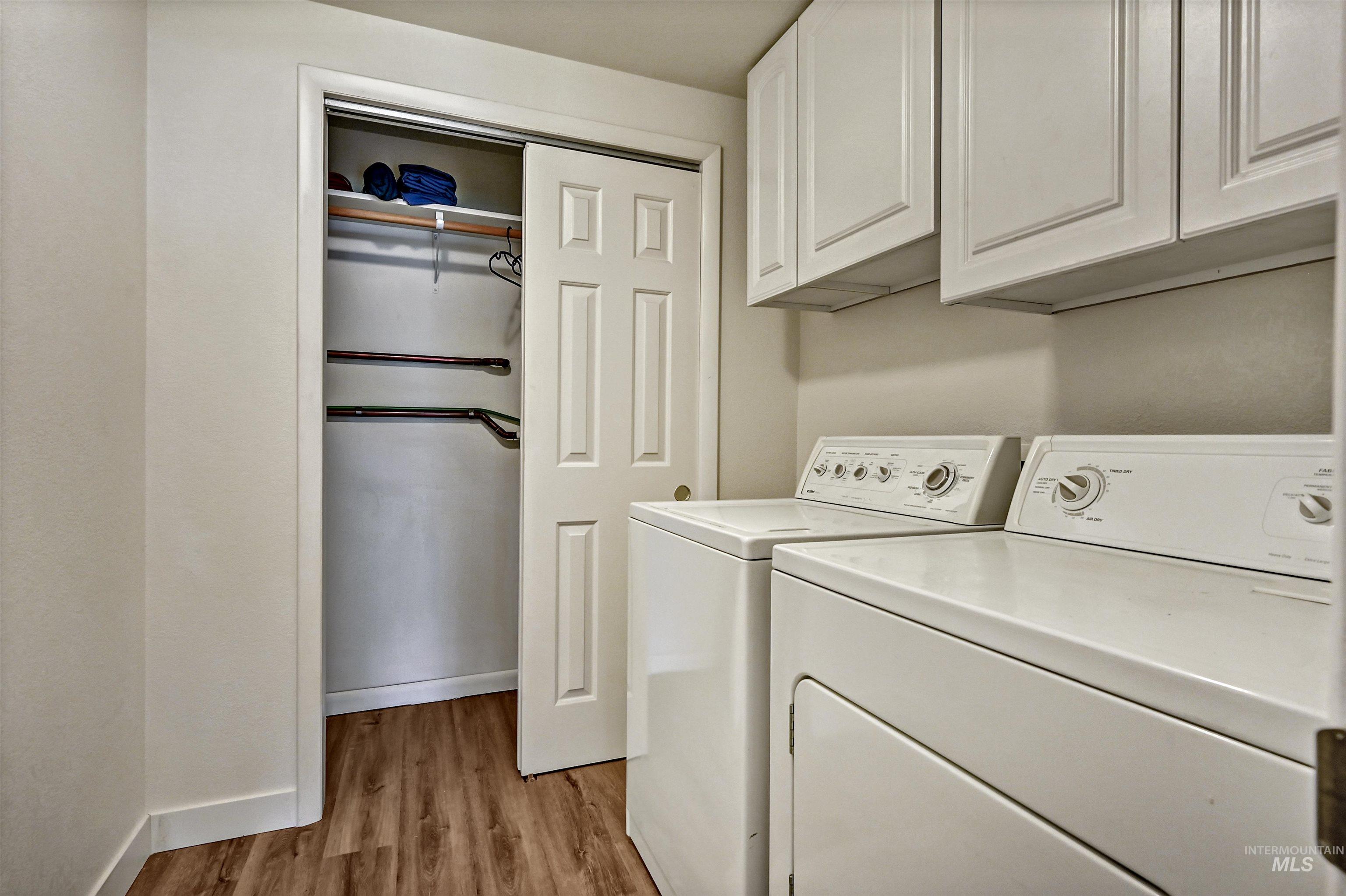 Laundry area featuring light wood-type flooring, washer and dryer, and cabinet space