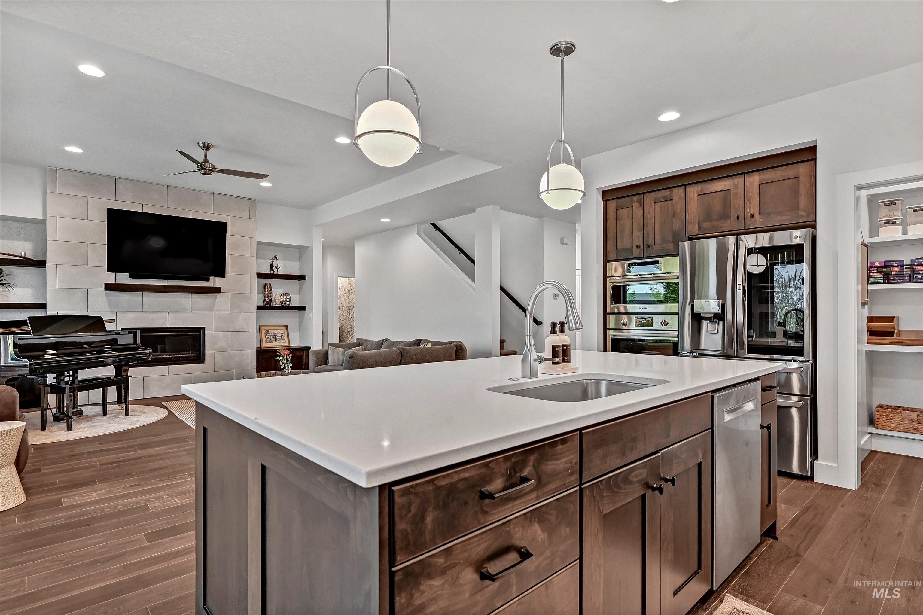 Kitchen with dark brown cabinetry, open floor plan, decorative light fixtures, a kitchen island with sink, and recessed lighting