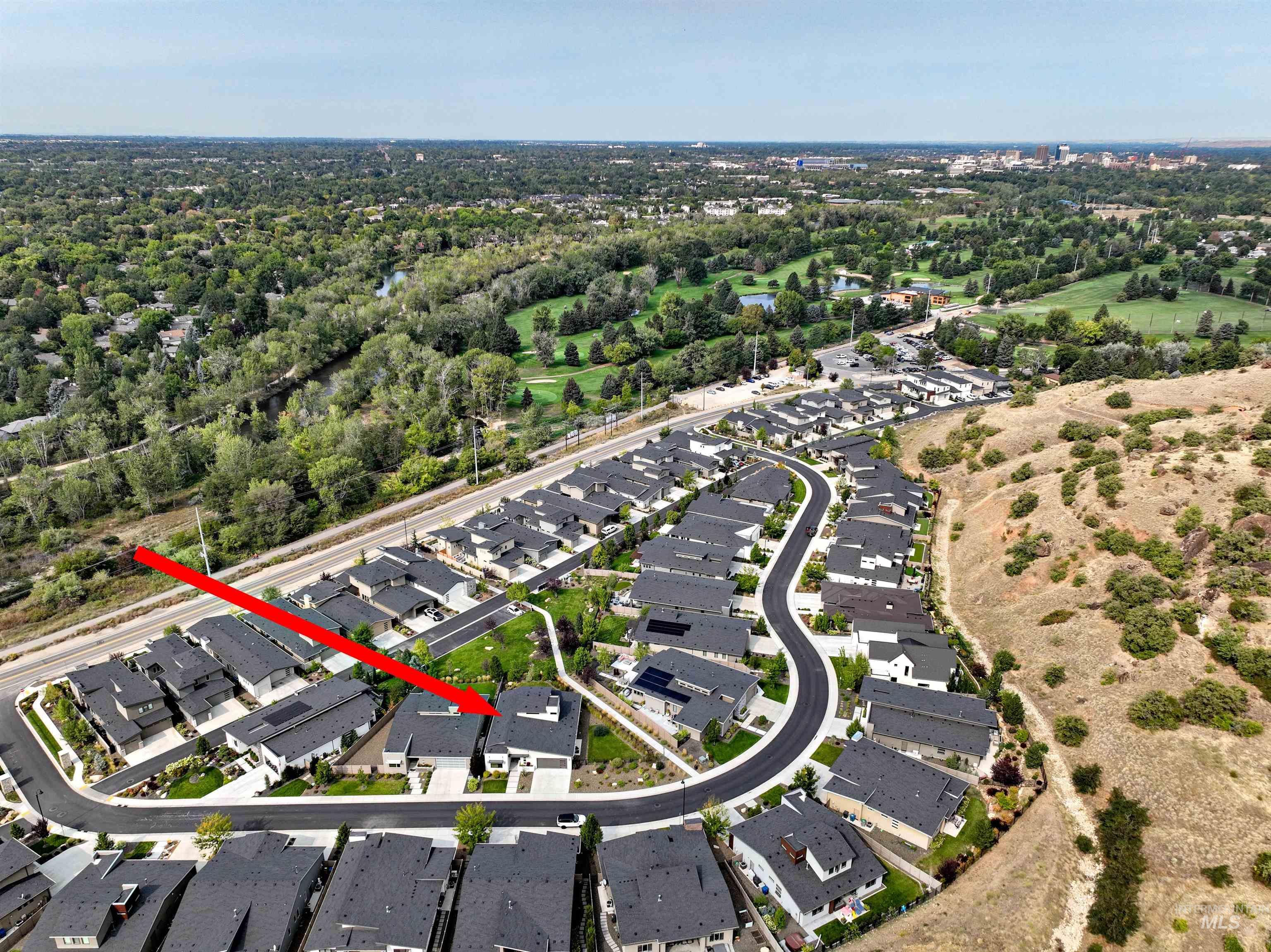 Aerial view of property's location featuring nearby suburban area and a tree filled landscape