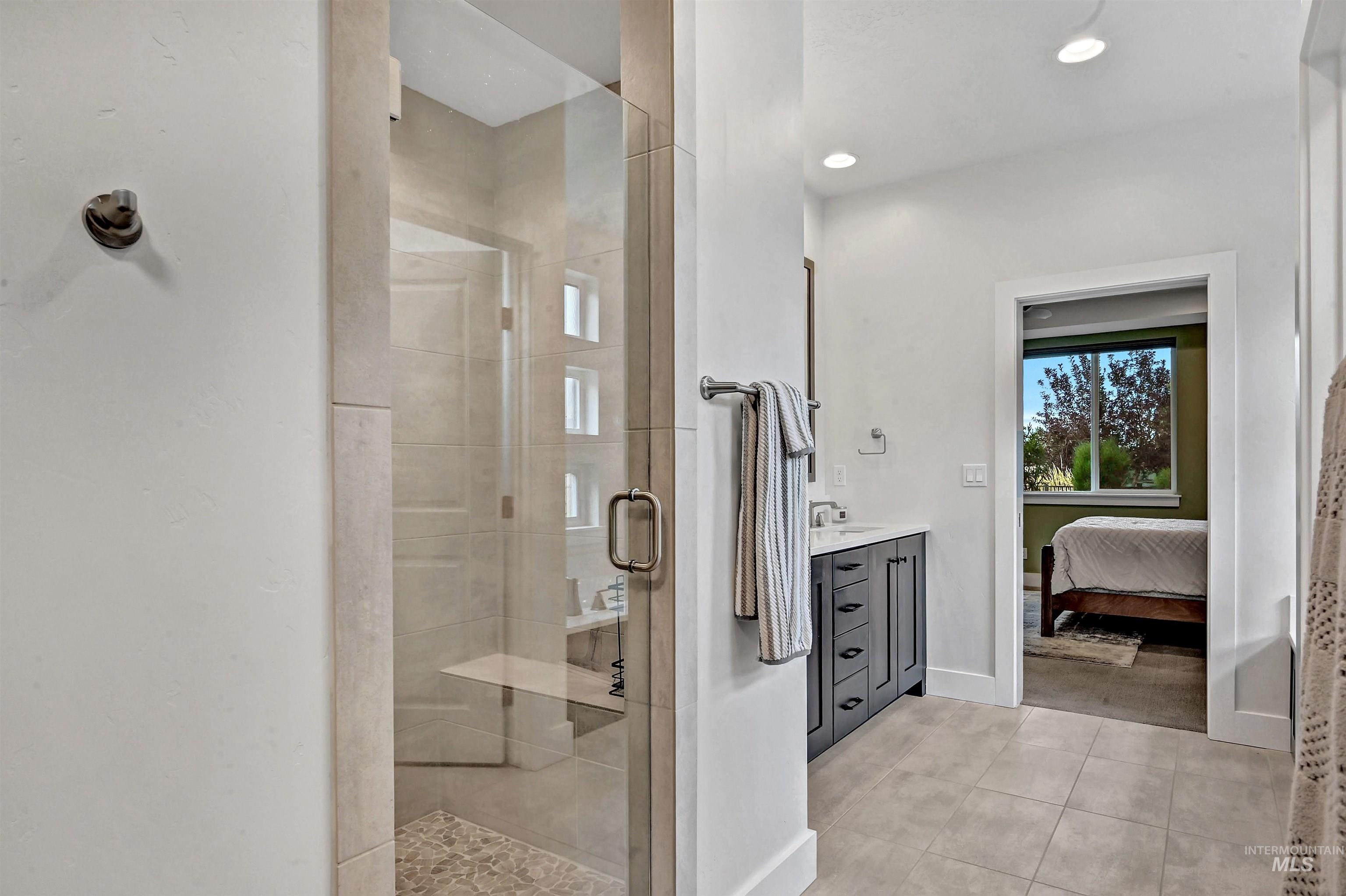 Ensuite bathroom with vanity, a stall shower, light tile patterned floors, and recessed lighting