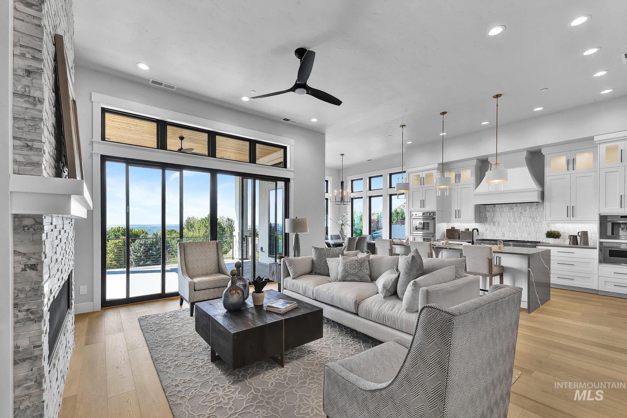 Living room with a fireplace, light wood-style floors, a ceiling fan, recessed lighting, and a chandelier