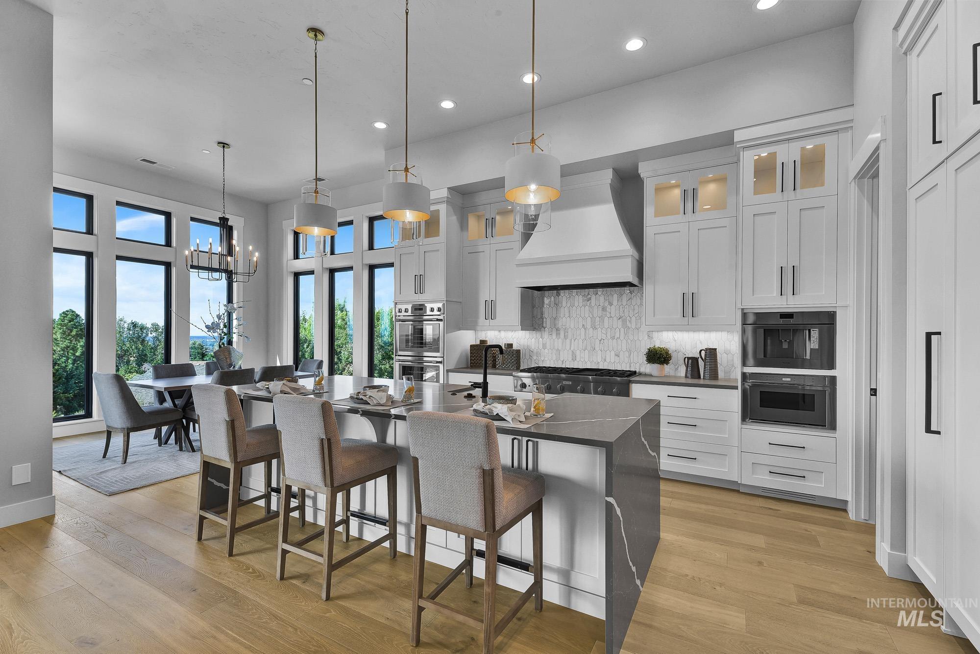 Kitchen with a kitchen bar, backsplash, white cabinets, a kitchen island with sink, and recessed lighting