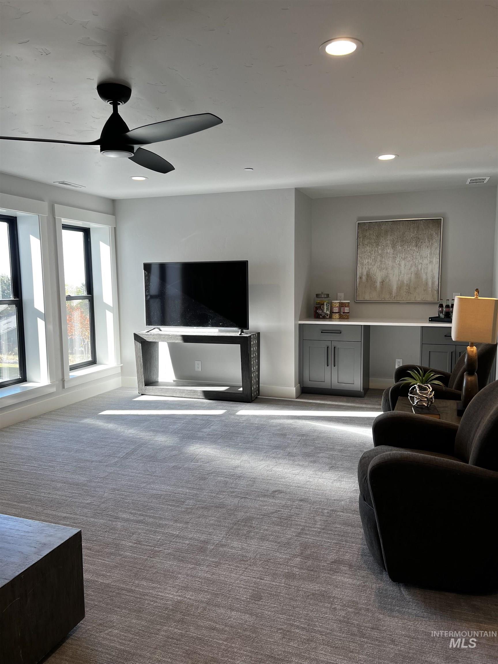 Living area with dark colored carpet, recessed lighting
