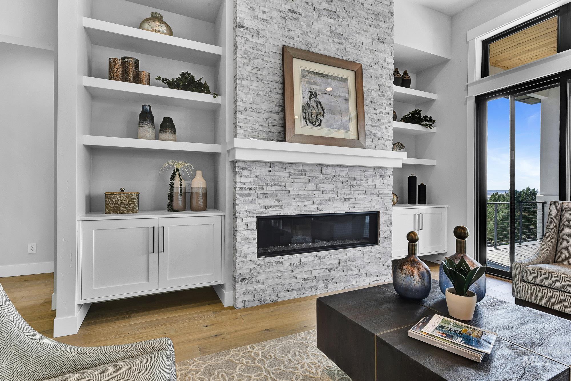 Living room with built in features, a fireplace, and light wood finished floors