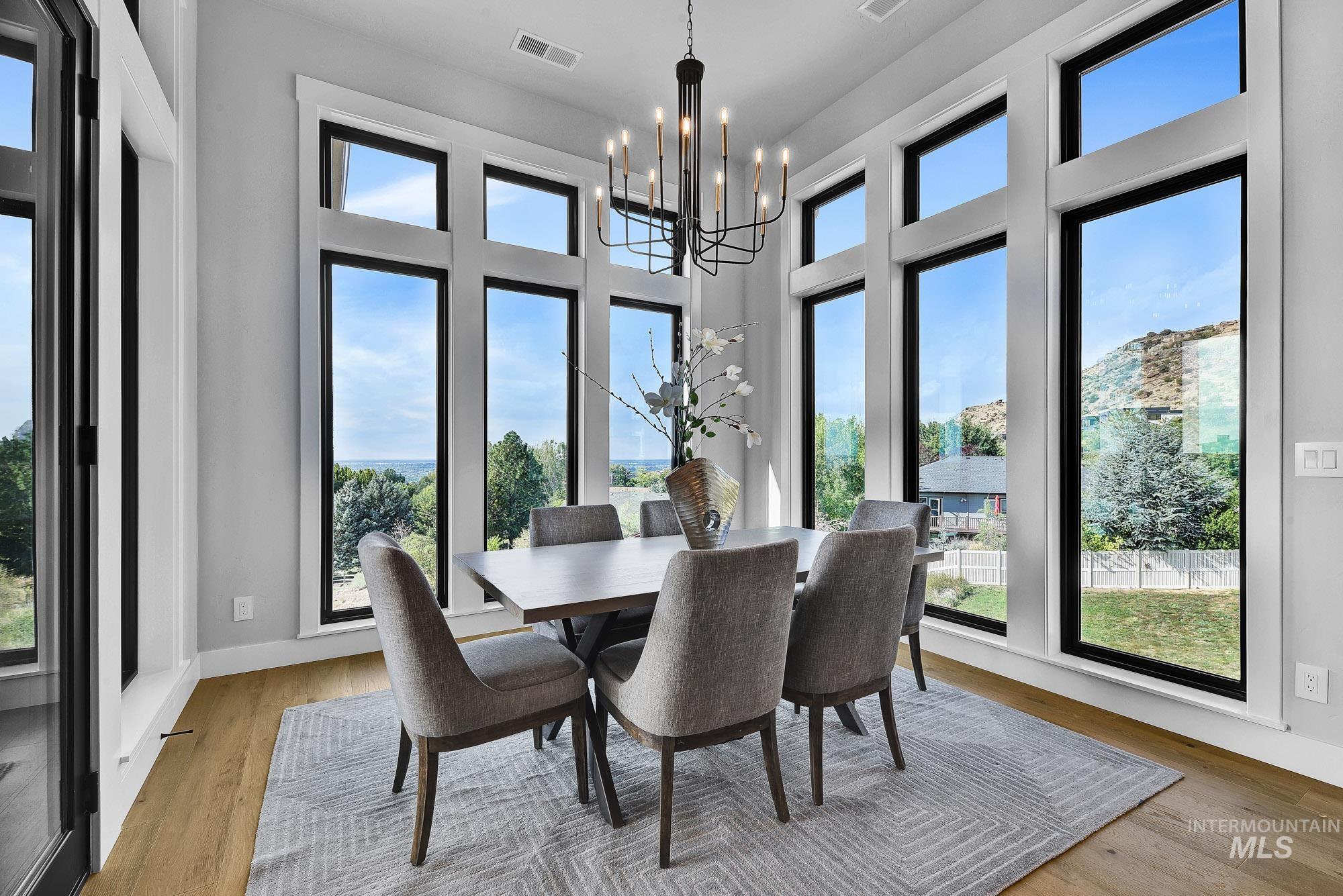Dining space with light wood-type flooring, a chandelier, and a high ceiling