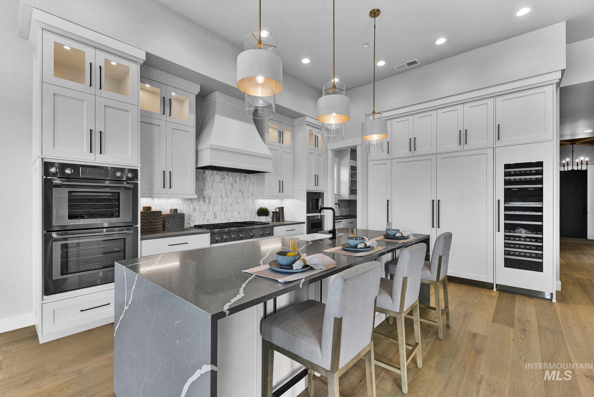 Kitchen featuring a breakfast bar, decorative light fixtures, tasteful backsplash, stainless steel appliances, and glass insert cabinets