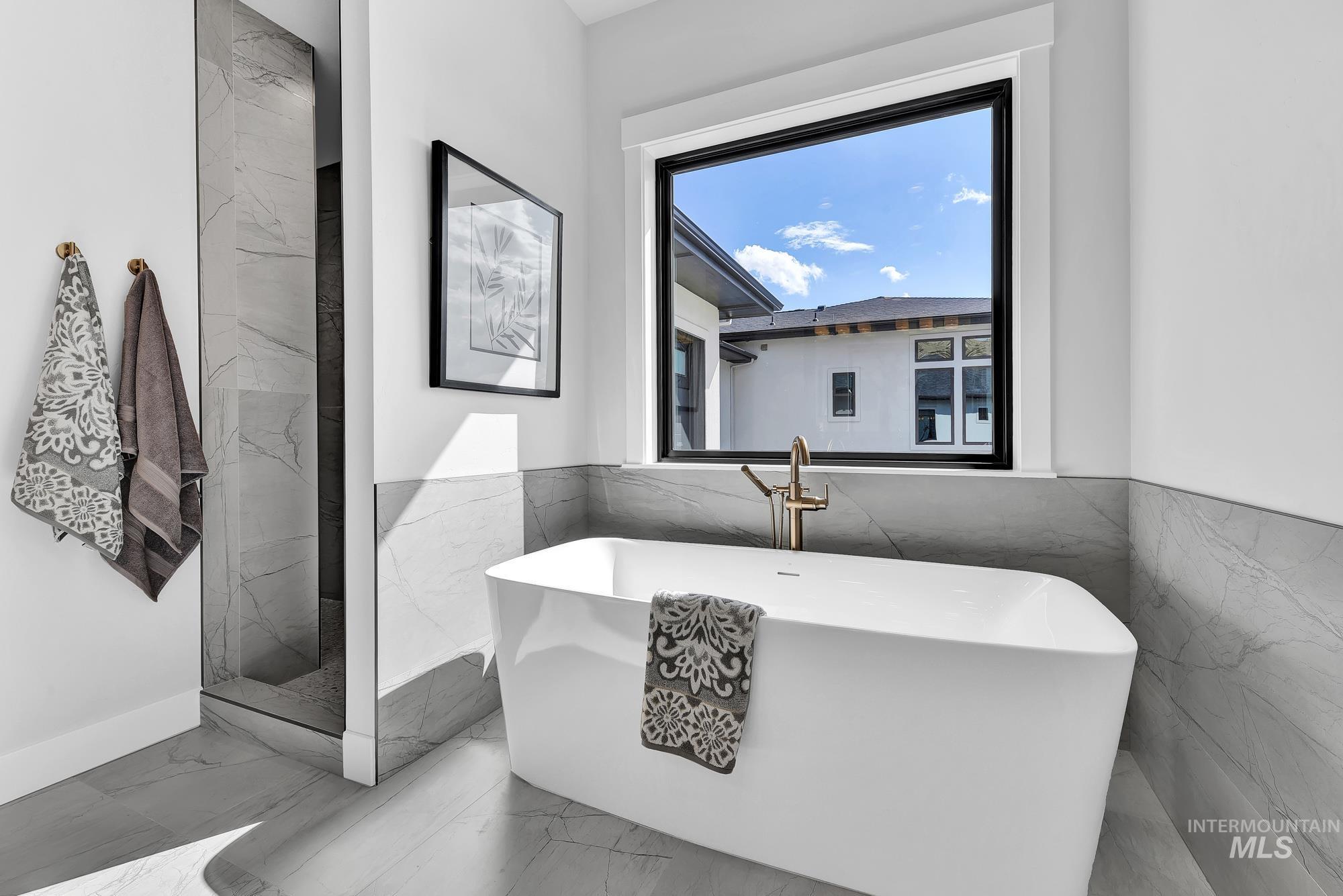 Full bathroom with a freestanding bath, a marble finish shower, marble finish floors, and tile walls
