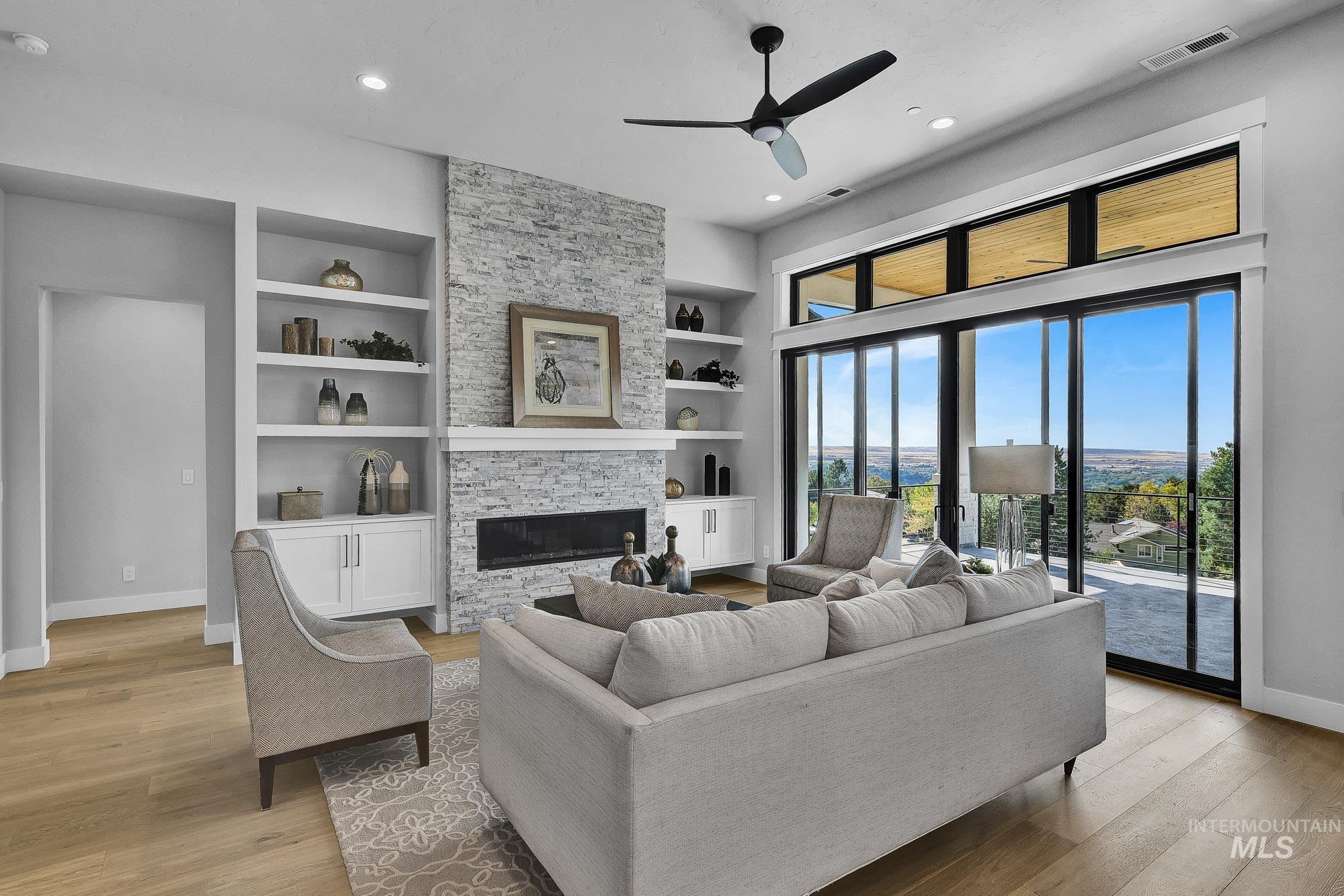 Living area with a fireplace, built in shelves, light wood-style flooring, a ceiling fan, and recessed lighting