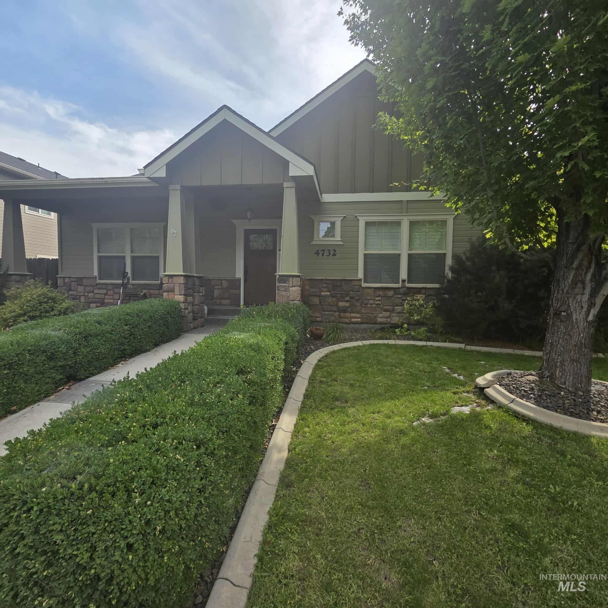 Craftsman-style home featuring stone siding, a front yard, and board and batten siding